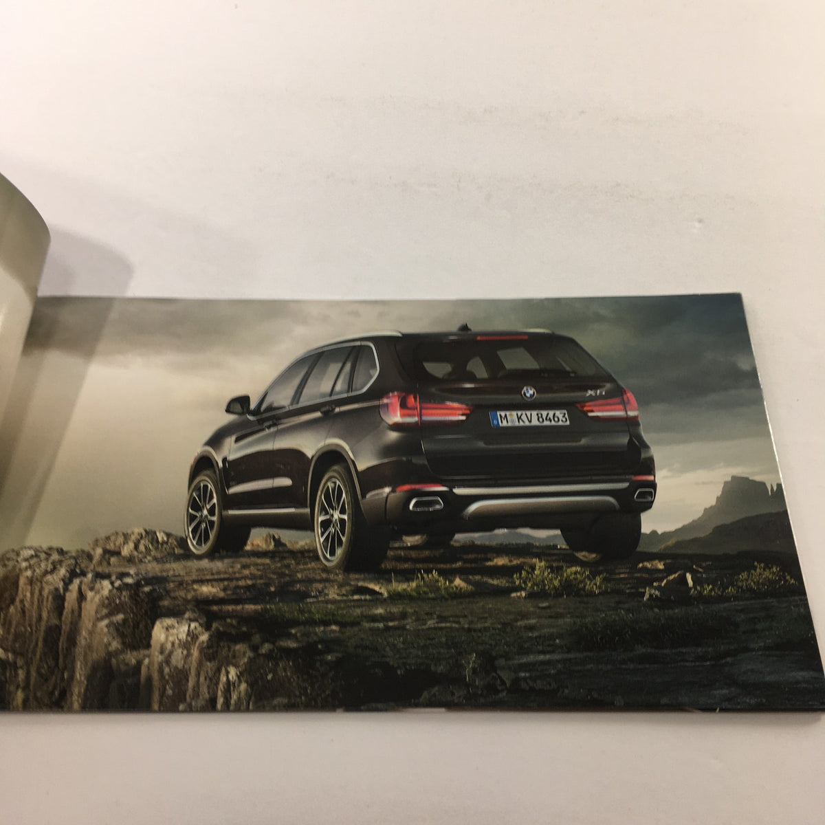 Rear view of the all-new 2014 BMW X-5 showcased in the dealership car auto brochure, highlighting its stylish design and landscape setting.