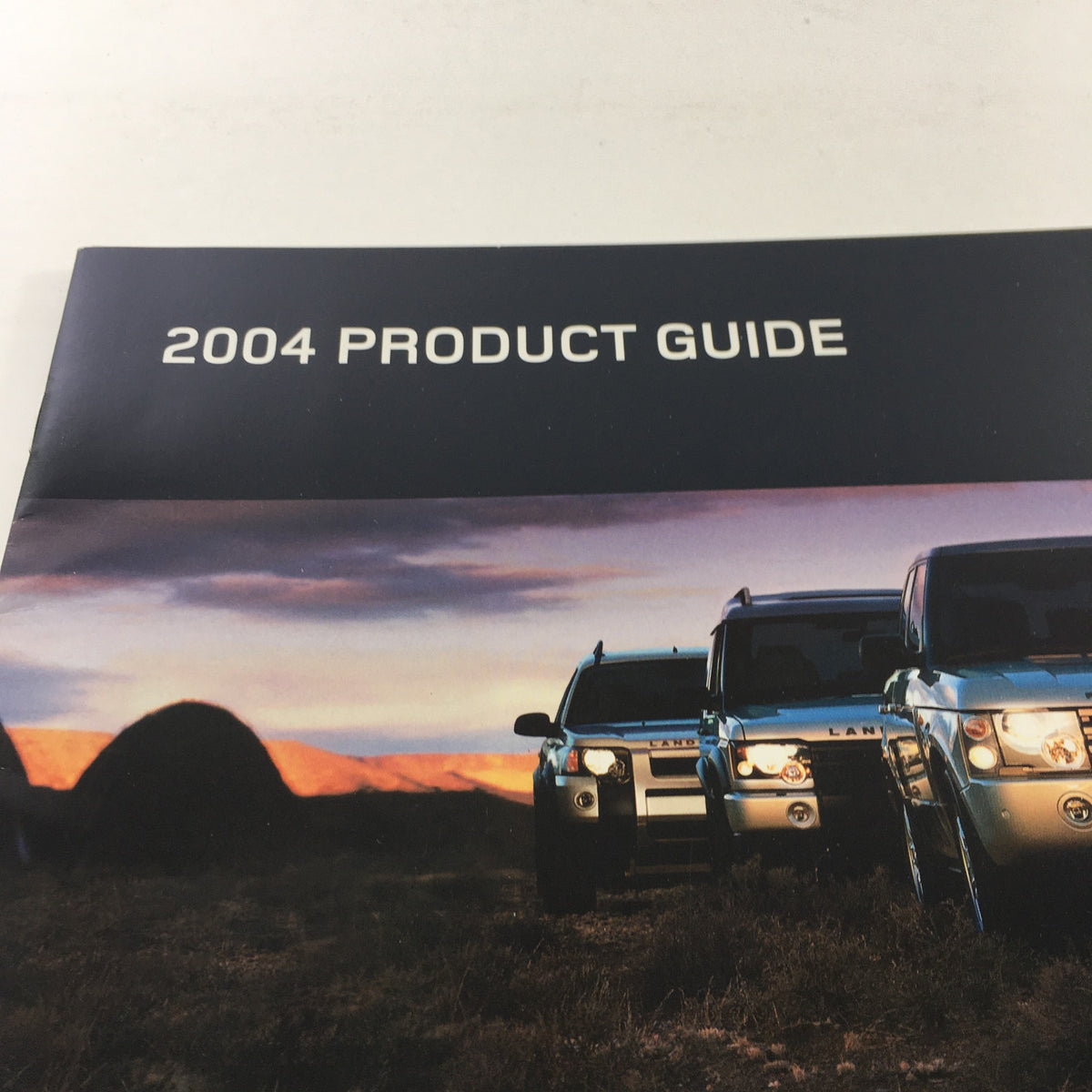 Close-up of the cover of the 2004 Land Rover Product Guide highlighting the title and a captivating landscape.