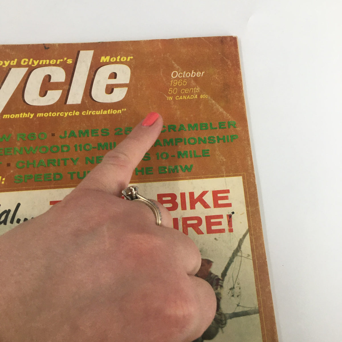 Hand pointing to the date on the cover of the VTG Cycle Magazine, October 1965, capturing the essence of vintage motorcycling history.