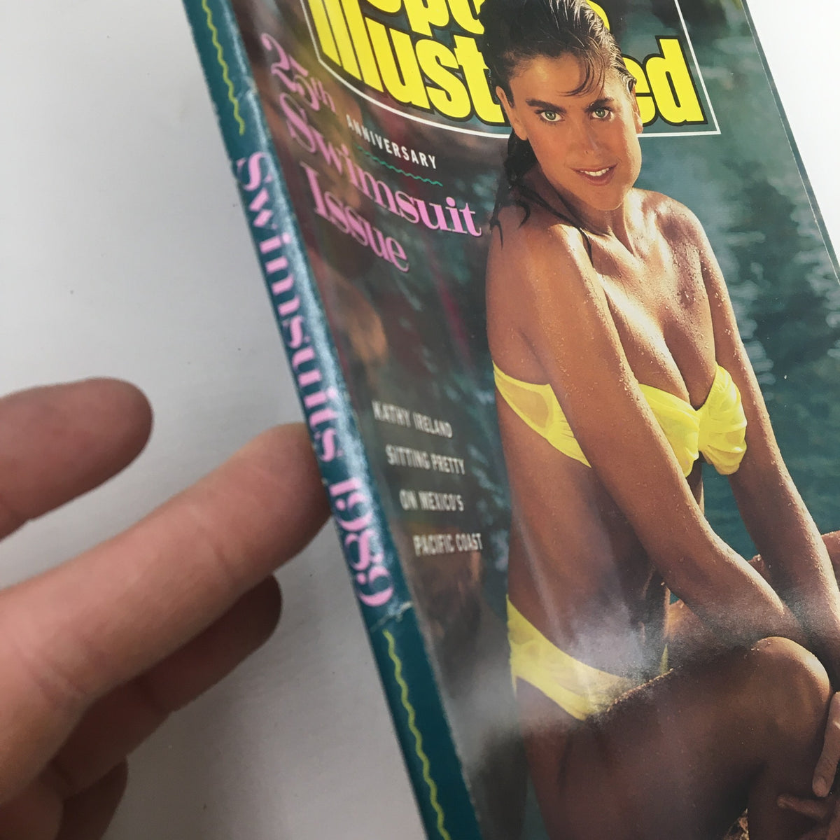 Side view of the VTG Sports Illustrated Magazine 1989 issue, showcasing the spine that highlights the 25th Anniversary Swimsuit Issue with Kathy Ireland on the cover.