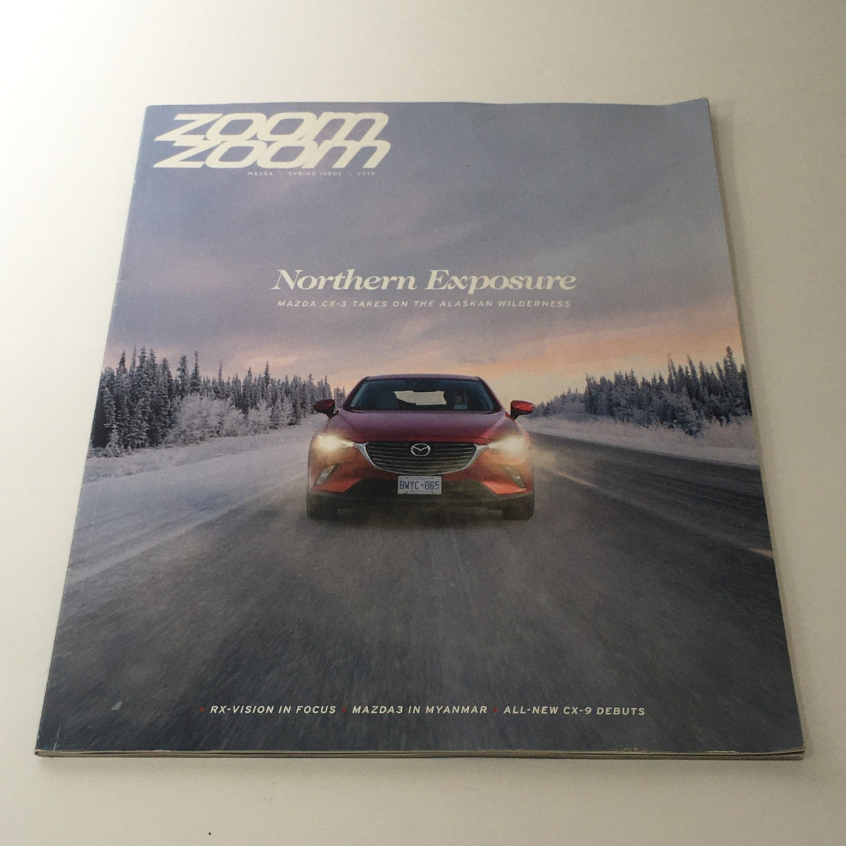 Cover of Spring 2016 Mazda RX-Vision CX-9 Debuts dealership car catalog brochure, featuring a Mazda CX-9 driving in a snowy landscape with a dramatic sky background.