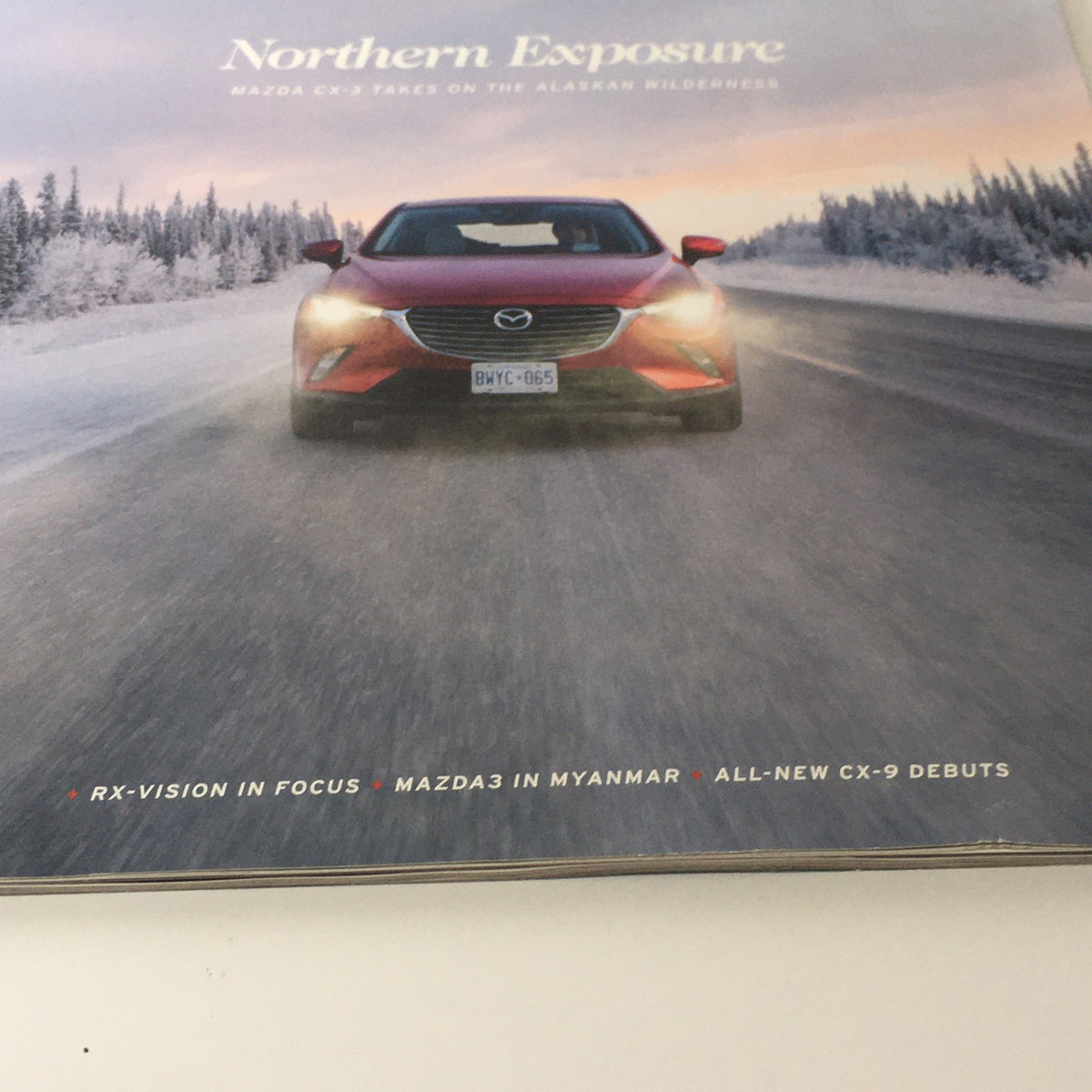Close-up of the cover of Spring 2016 Mazda RX-Vision CX-9 Debuts dealership car catalog brochure, highlighting the Mazda CX-9 with the text 'Northern Exposure.'