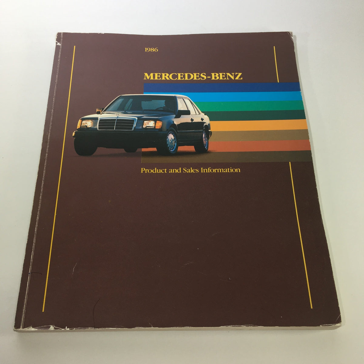 1986 Mercedes-Benz Product and Sales Information Brochure cover showcasing a black Mercedes-Benz car with a colorful background.