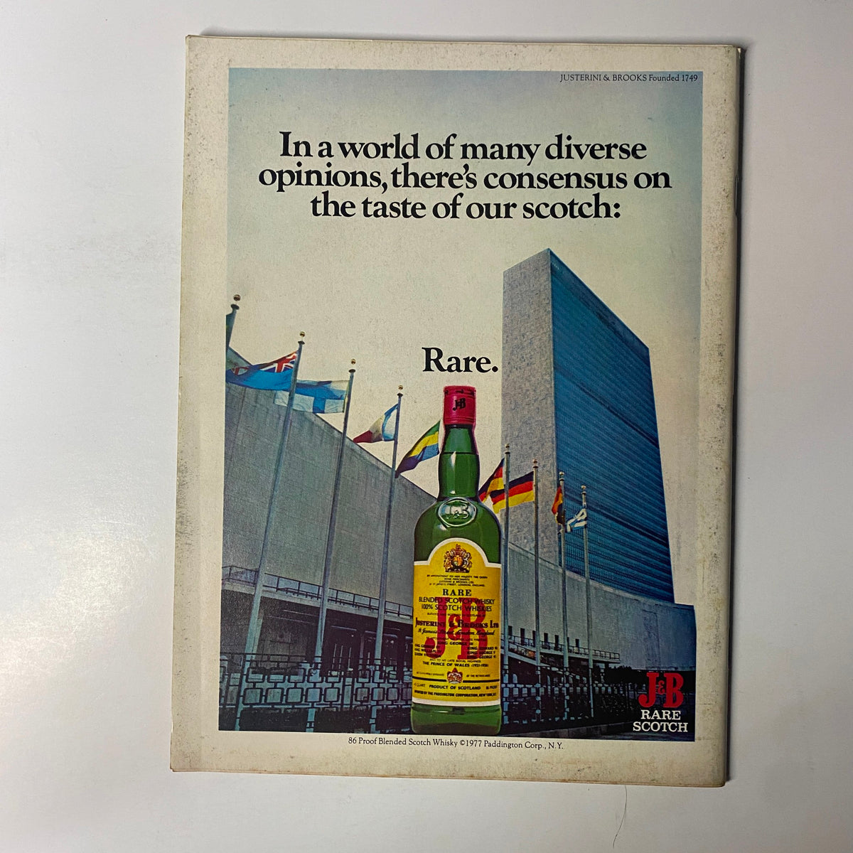 Forbes Magazine March 15, 1977 - Advertisement for J&B Rare Scotch featuring a bottle in front of the United Nations building with the slogan 'In a world of many diverse opinions, there’s consensus on the taste of our scotch: Rare.'.