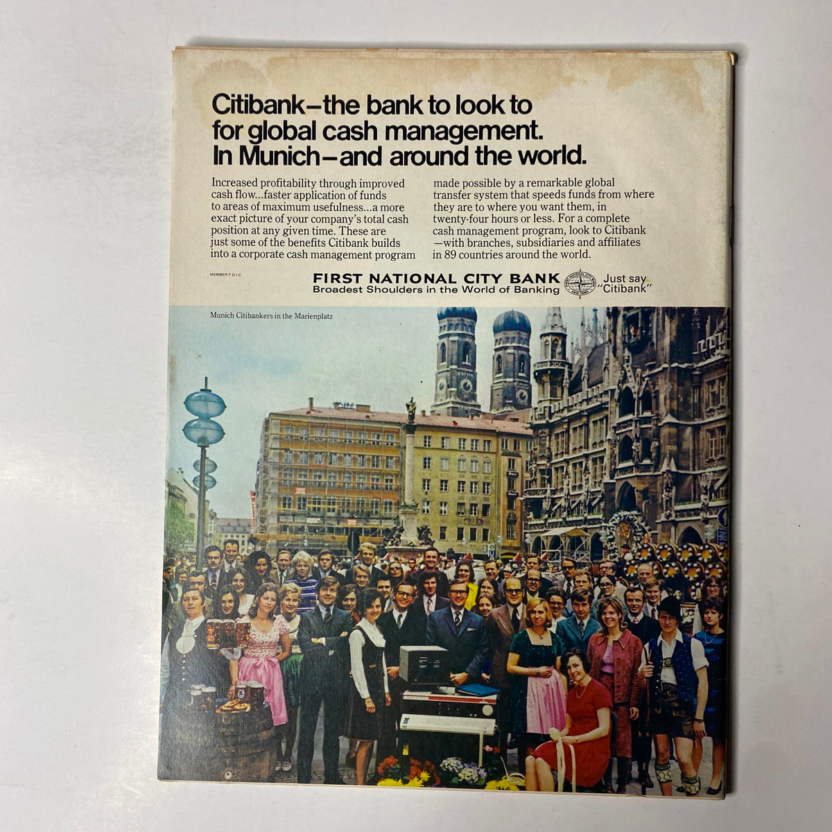 Vintage advertisement from Forbes Magazine dated October 1, 1972, featuring Citibank's cash management services in Munich, with a large group of professionals in traditional attire gathered in a public square near historic buildings.