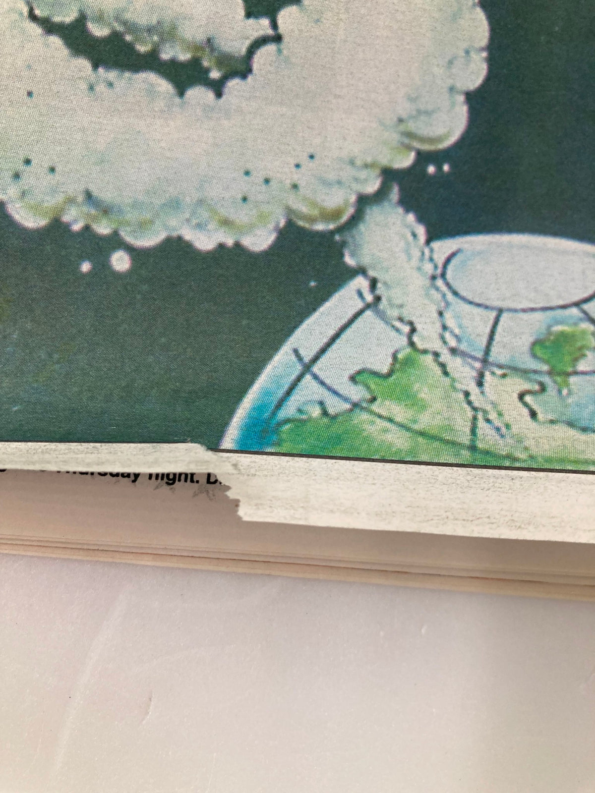 Close-up of the bottom section of the Dallas Cowboys Weekly Newspaper from September 5, 1998, Vol 24 #12. The image highlights a torn edge and the illustration showing a globe with faint details in the background.