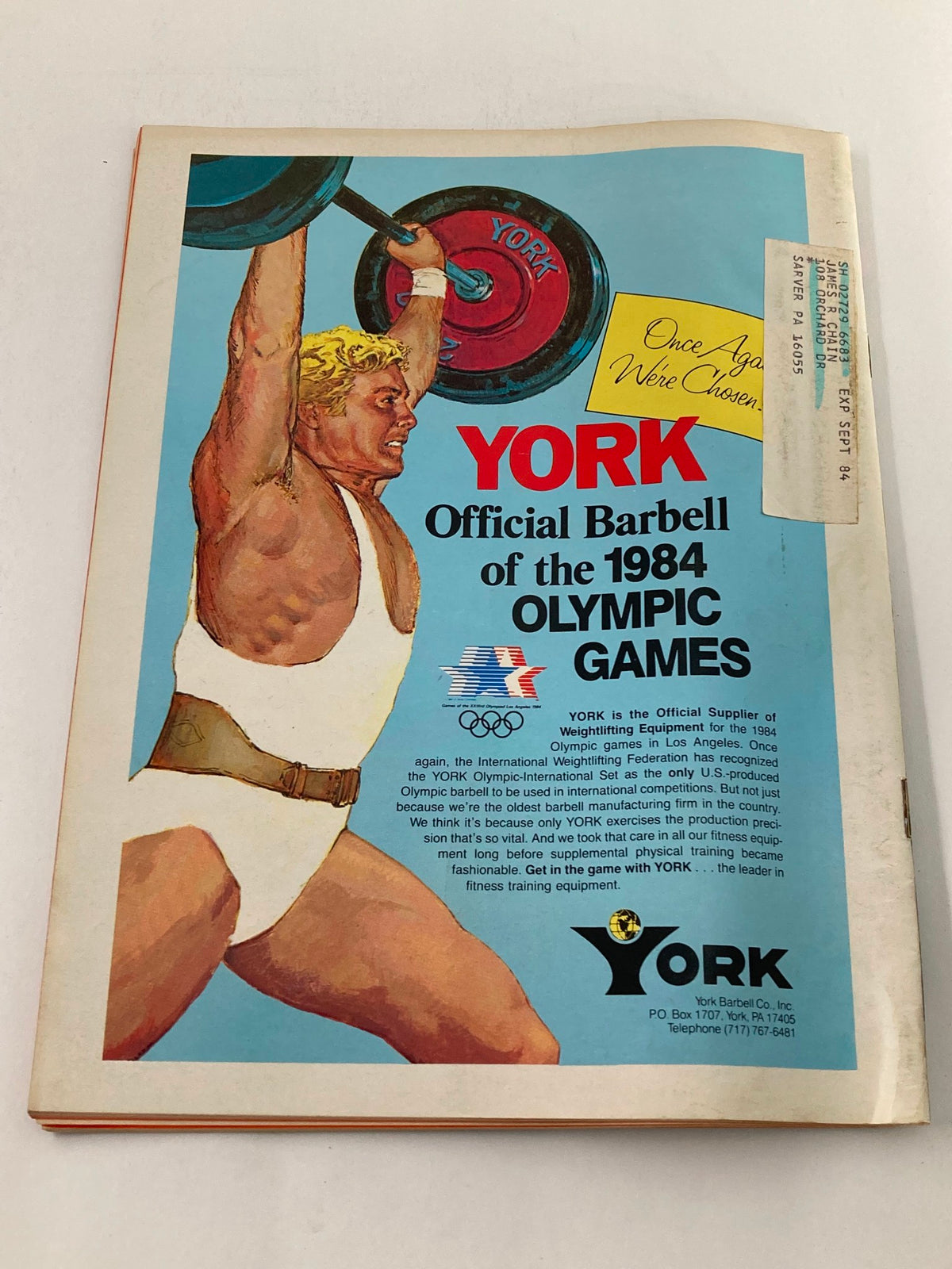 Promotional page for YORK Official Barbell of the 1984 Olympic Games found in the January 1984 VTG Strength & Health Magazine, showcasing a weightlifter with a YORK branded barbell.