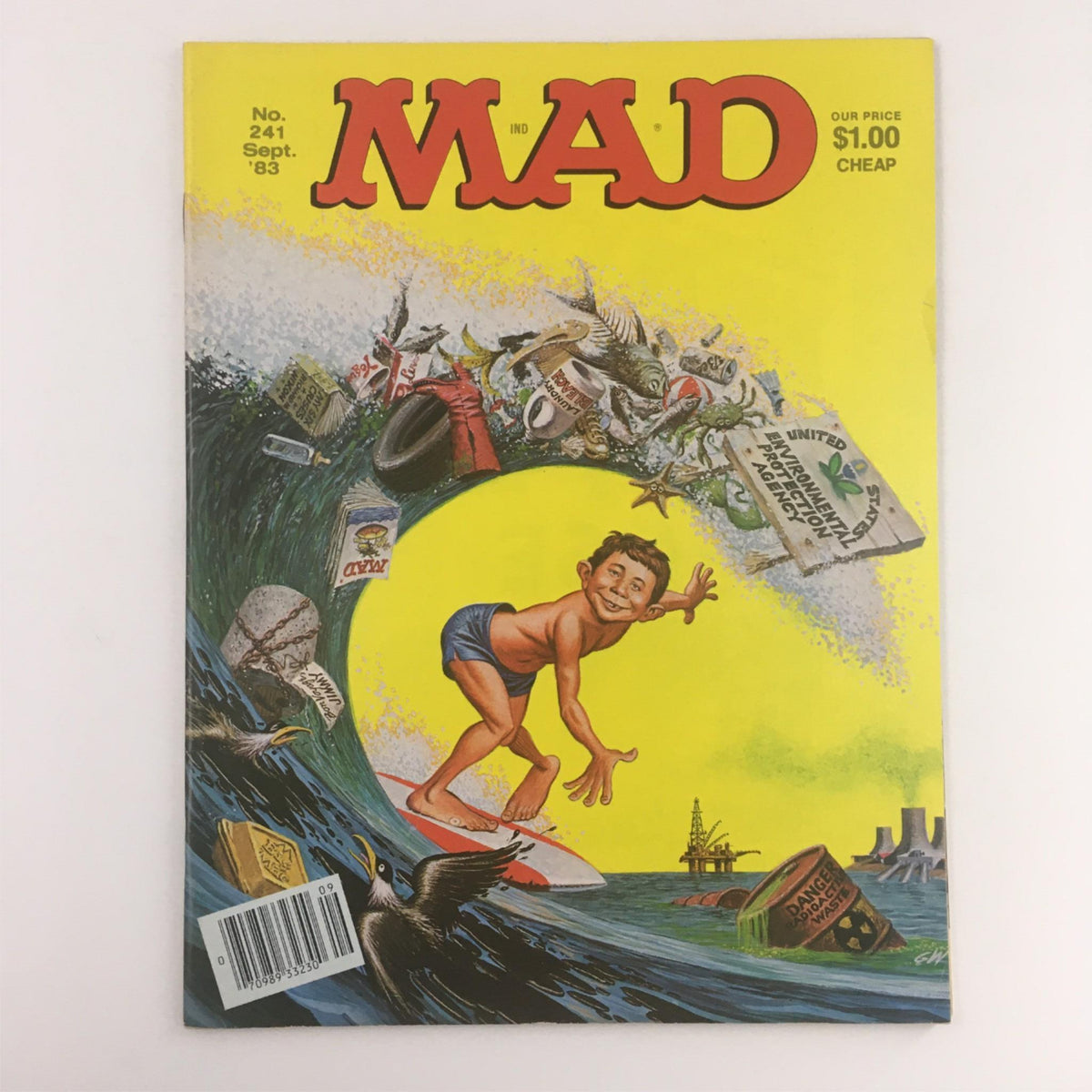 Cover of Mad Magazine September 1983, featuring the title 'MAD' prominently at the top. The colorful cover showcases a child surfing on a wave with various pollution-themed items including barrels and trash, highlighting the issue's theme 'Surfing Polluted Wave,' No. 241. This issue is a fine collectible rated FN 6.0.