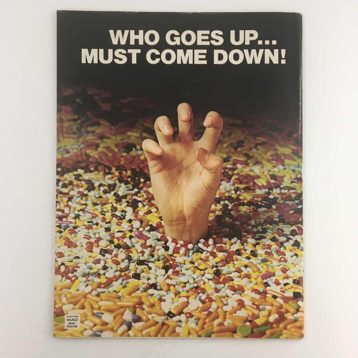 The back cover of Mad Magazine March 1975 No. 173, depicting a hand emerging from a colorful pile of candy and pills with the phrase 'Who Goes Up... Must Come Down!' illustrating the magazine's playful and ironic style.