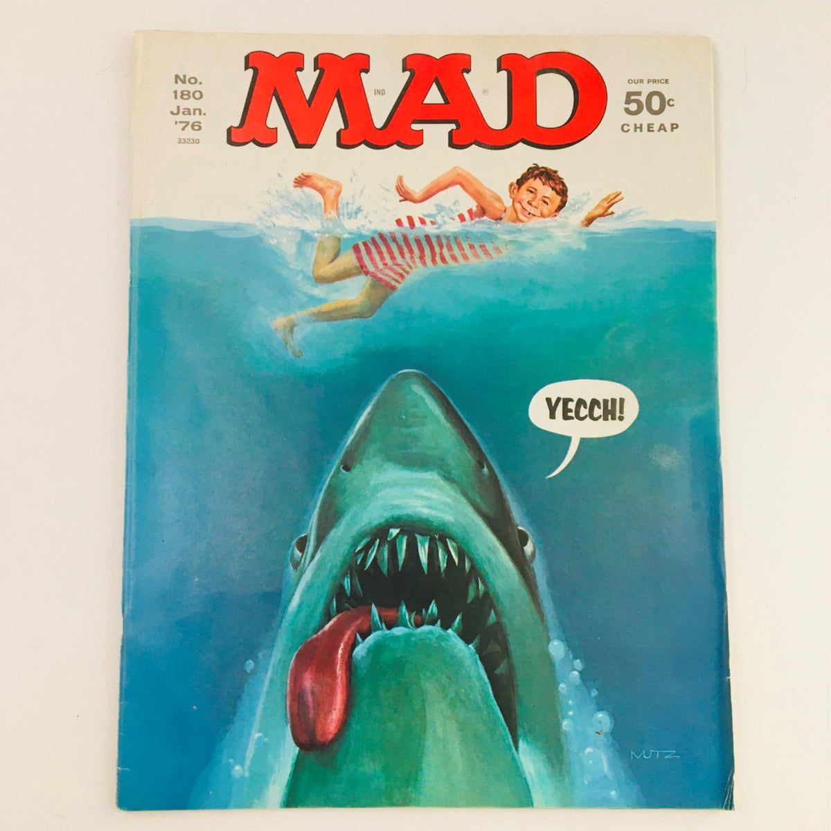 Cover of Mad Magazine January 1976 No. 180 Jaws, featuring a humorous shark illustration with a swimmer and the text 'Yecch!'. This Fine/FN 6.0 graded vintage magazine illustrates the iconic parody of the blockbuster film Jaws, capturing 1970s pop culture.