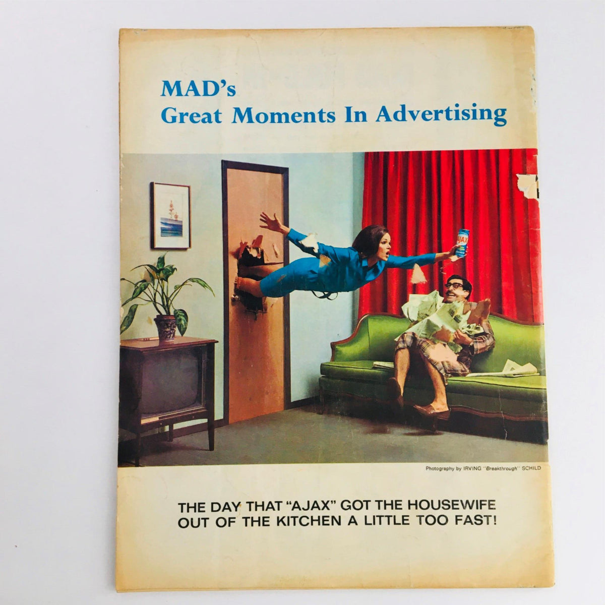 Back cover of Mad Magazine featuring the title 'MAD's Great Moments In Advertising', showcasing a playful scene of a woman bursting through a door while holding a cleaning product, illustrating the magazine's comedic take on advertising.
