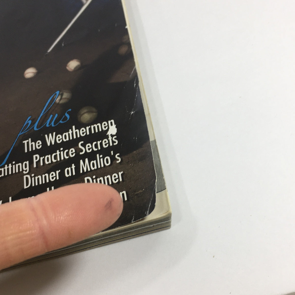 Close-up of the spine of Yankees Magazine May 2011 Volume #32-3, highlighting signs of wear including a finger pointing to the edge, indicative of its vintage condition.