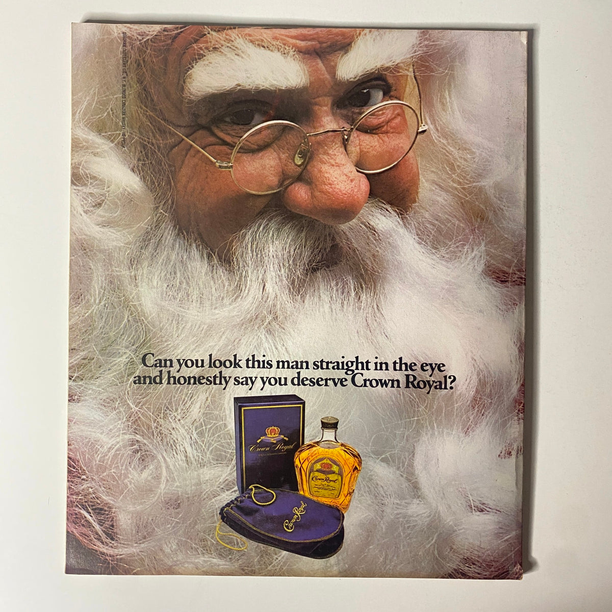 Cover of a vintage advertisement featuring a thoughtful Santa Claus promoting Crown Royal whiskey with an intriguing question.