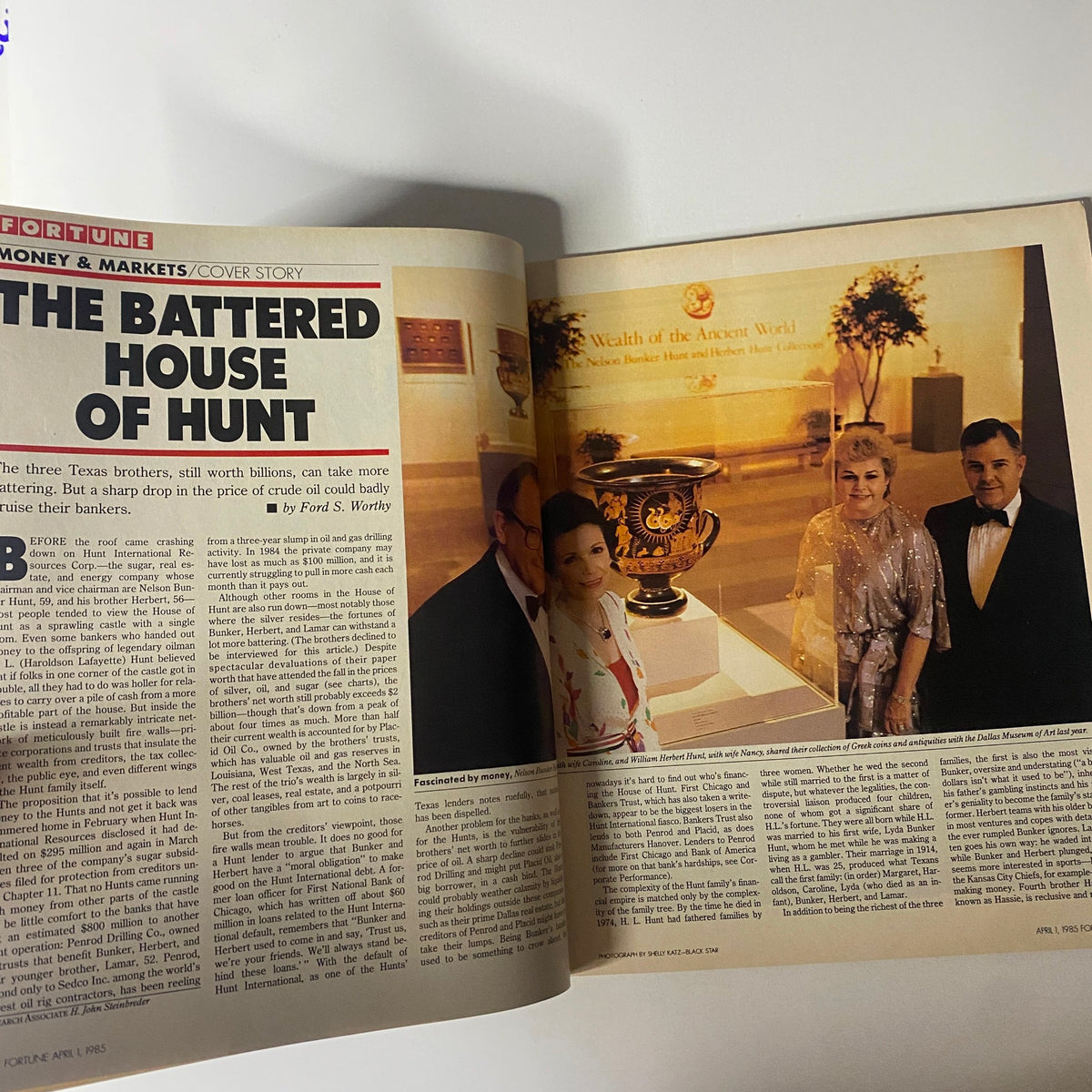 An article page from the April 1, 1985 Fortune Magazine titled 'The Battered House of Hunt', featuring images of the Hunt brothers in an elegant setting, emphasizing their financial struggles.