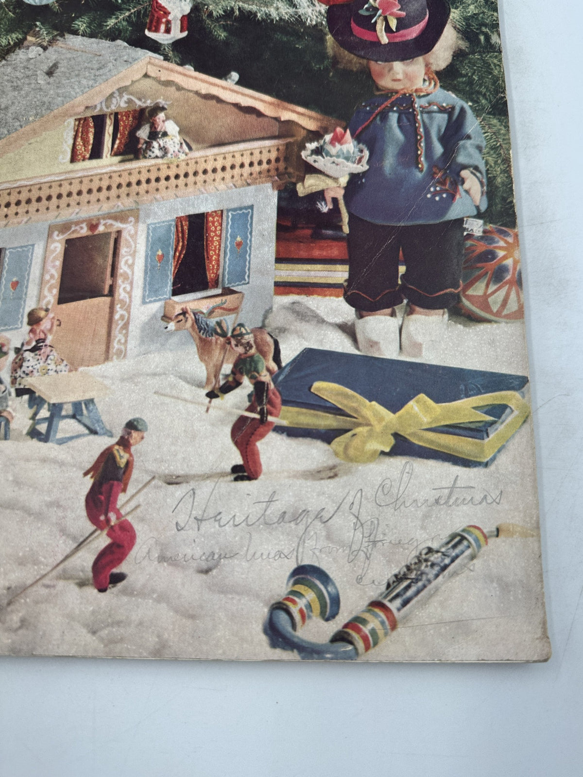 Decorative Christmas scene from House Beautiful Magazine, December 1937, featuring toys and a doll in a snowy layout, showcasing vintage holiday decorations.