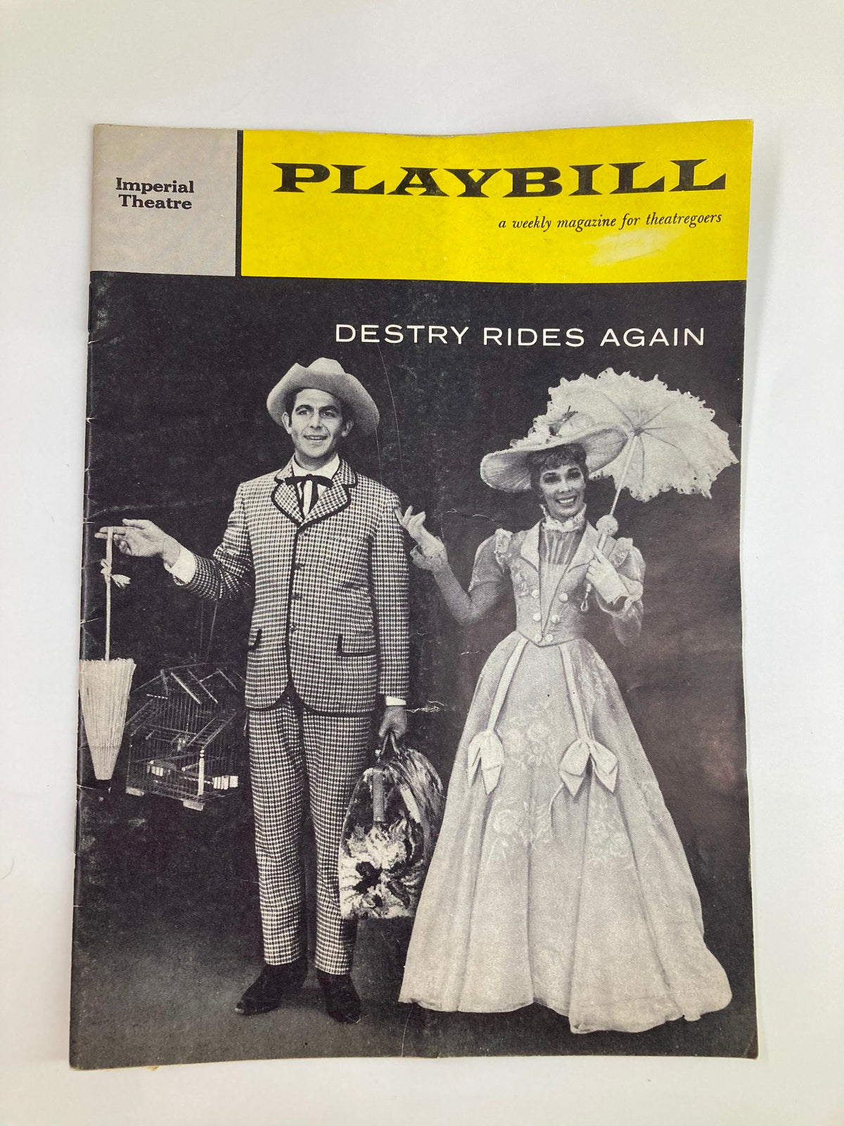 1959 Playbill for 'Destiny Rides Again' featuring a stylishly dressed couple, one in a checked suit and the other in a flowing gown with an umbrella, showcasing the theatrical charm of the Imperial Theatre.