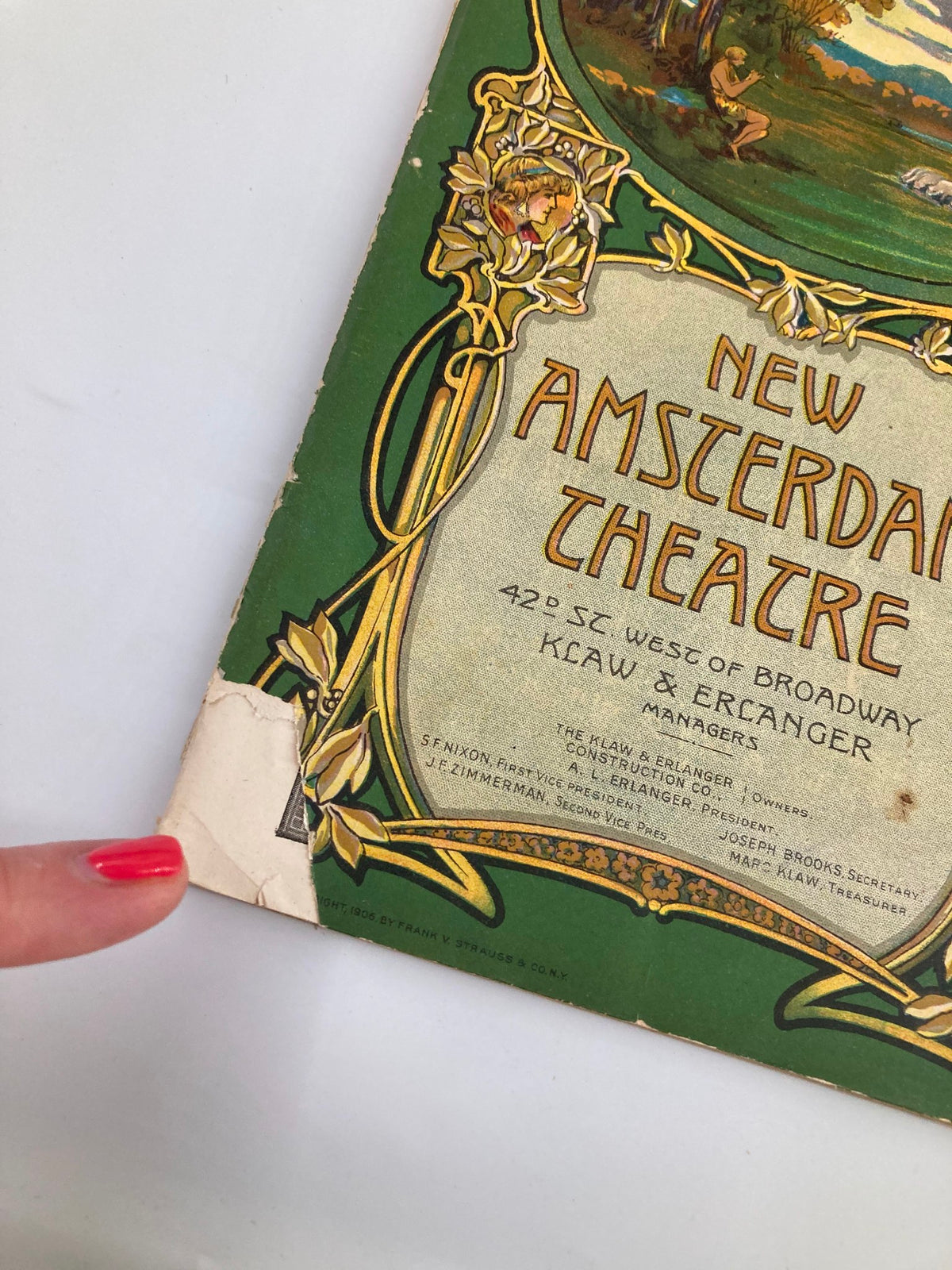 Close-up of the bottom corner of the 1913 New Amsterdam Theatre Playbill featuring the title 'New Amsterdam Theatre' and showcasing signs of wear, emblematic of its age.
