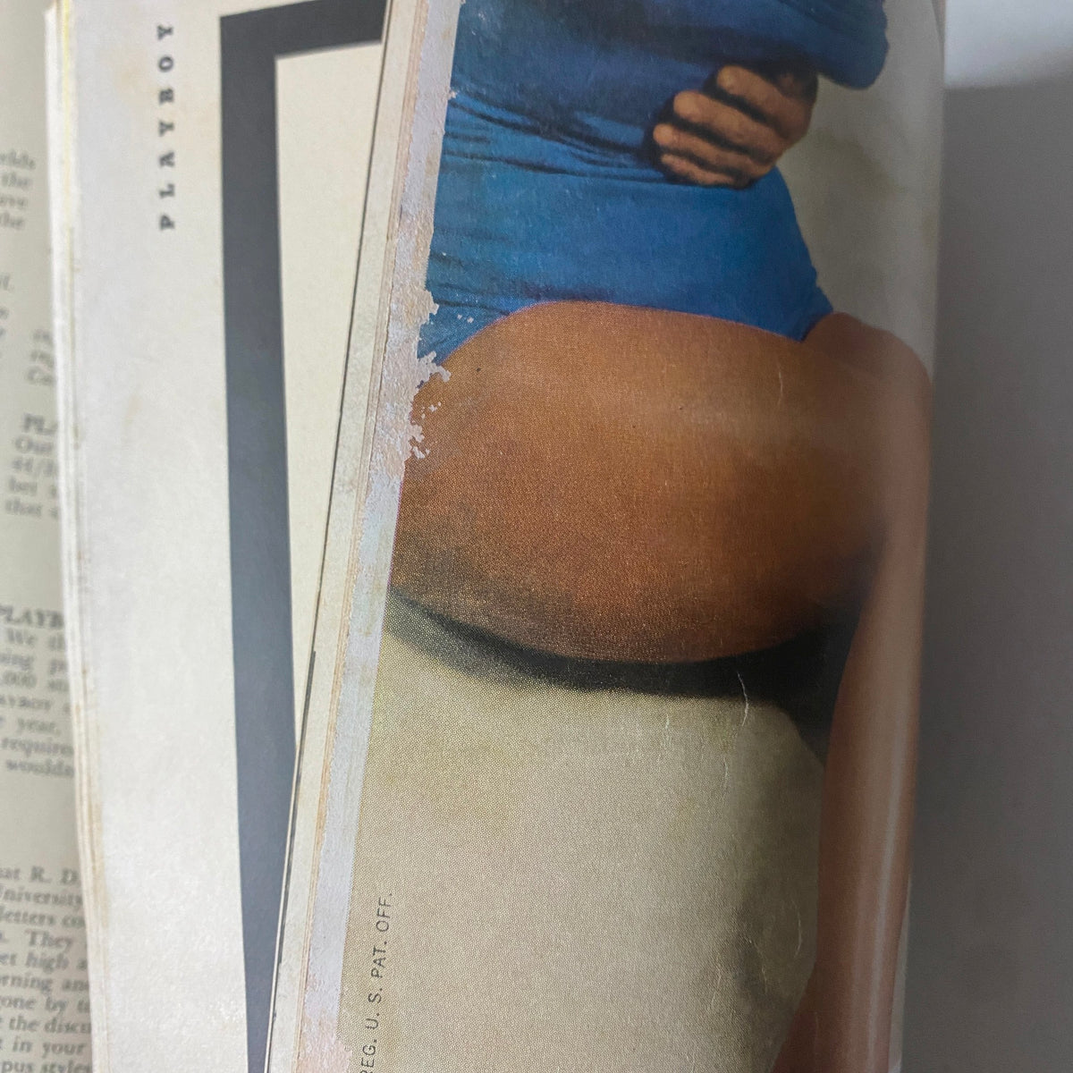 Close-up image of a page from Playboy Magazine July 1955, showing a portion of a pictorial featuring a model in a blue swimsuit, reflecting the magazine's vintage aesthetic.