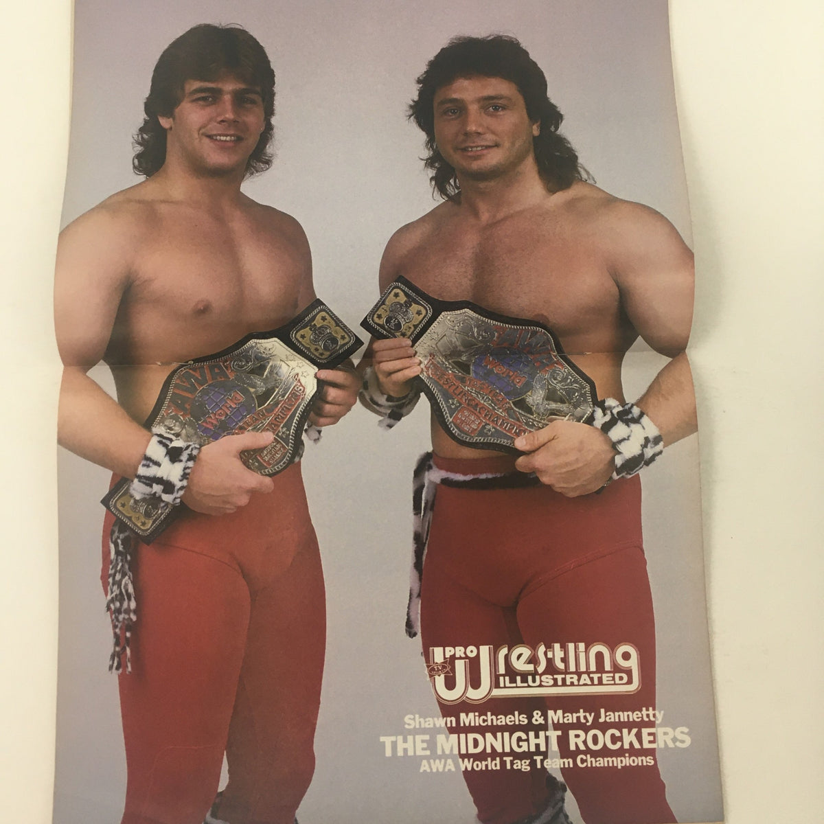Image of Shawn Michaels and Marty Jannetty, the Midnight Rockers, holding AWA World Tag Team Championship belts in Pro Wrestling Illustrated July 1987.
