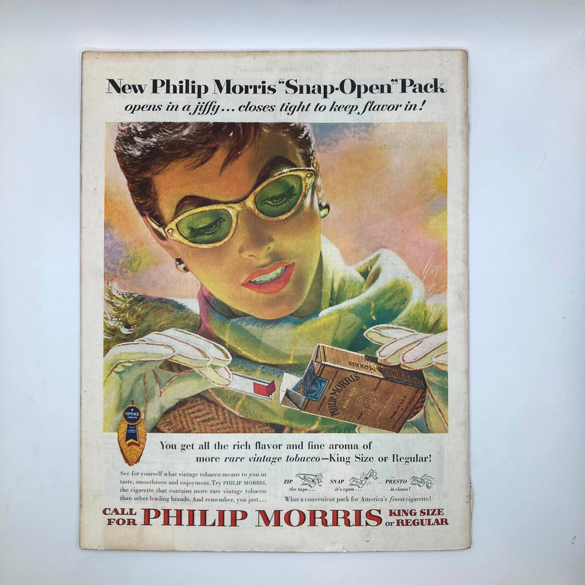 Advertisement page from the Saturday Evening Post, featuring a woman with green sunglasses promoting Philip Morris 'Snap-Open' tobacco pack.