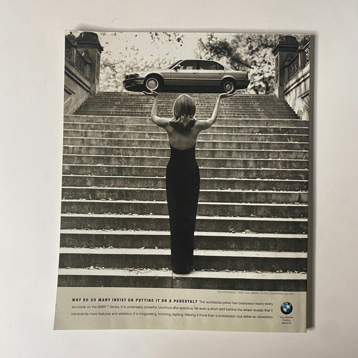 Artistic black and white image from Martha Stewart Living Magazine April 1997, showcasing a woman holding a miniature car above her head while standing on stairs, evocative of the luxury lifestyle promoted in the magazine.