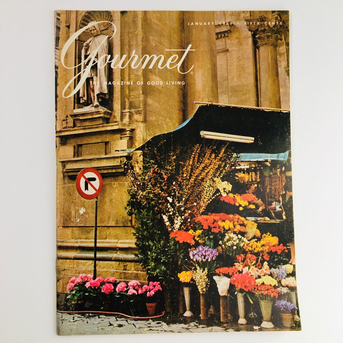 Cover of the Gourmet Magazine of Good Living from January 1969 featuring vibrant flowers and a picturesque street scene, showcasing a touch of culinary history and literature with William Faulkner's feature.