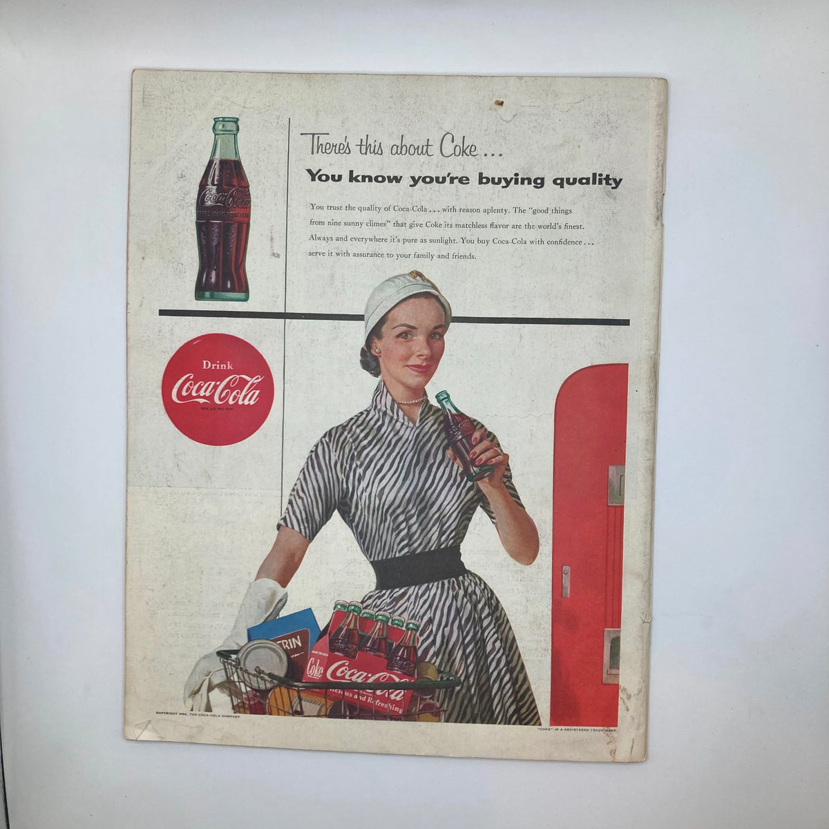 Vintage advertisement for Coca-Cola from July 10, 1954, featured in The Saturday Evening Post Magazine, showcasing a woman holding a Coke bottle with a shopping basket.