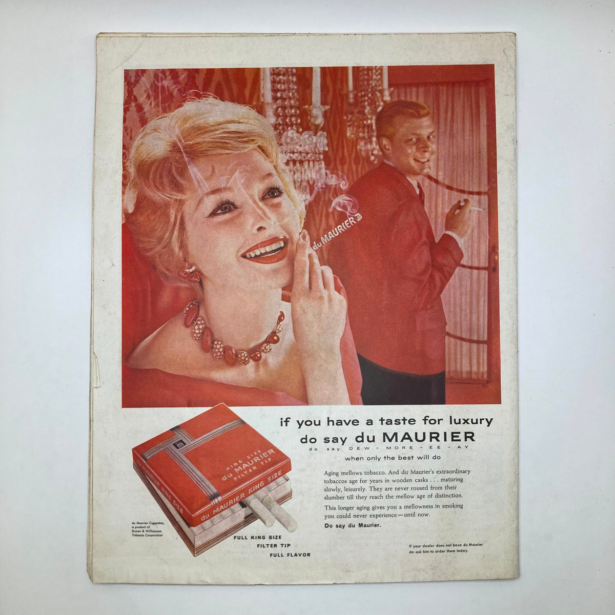 Vintage advertisement for du Maurier cigarettes featuring a glamorous woman smiling with red lipstick and a necklace, alongside a man in a suit, encapsulating the luxury lifestyle of the late 1950s. Part of the Saturday Evening Post Magazine from September 7, 1958, titled 'First Day of School - Utz'.