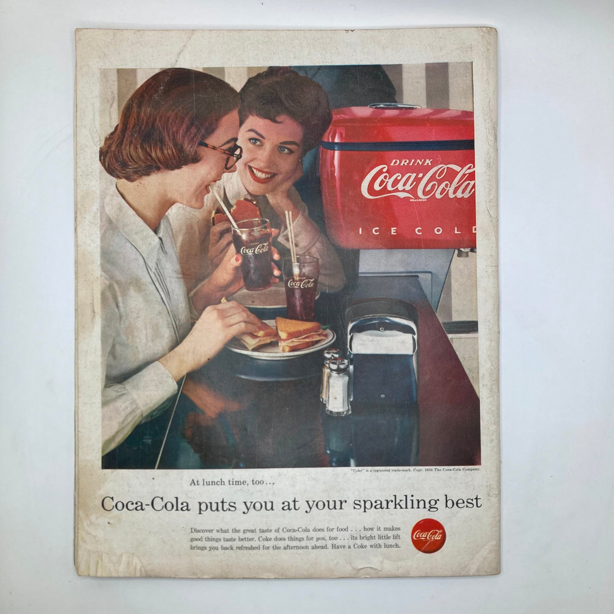 Vintage advertisement from the Saturday Evening Post Magazine, November 24, 1956 promoting Coca-Cola, depicting two women enjoying drinks and lunch, capturing a nostalgic 1950s dining experience.
