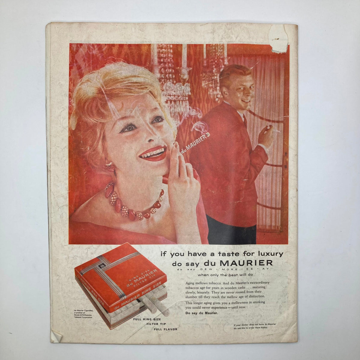 Vintage advertisement from the Saturday Evening Post Magazine September 6 1958 featuring a glamorous woman with blonde hair wearing jewelry, promoting du Maurier cigarettes with a stylish design and a man in the background. This classic magazine showcases the aesthetics of the late 1950s.