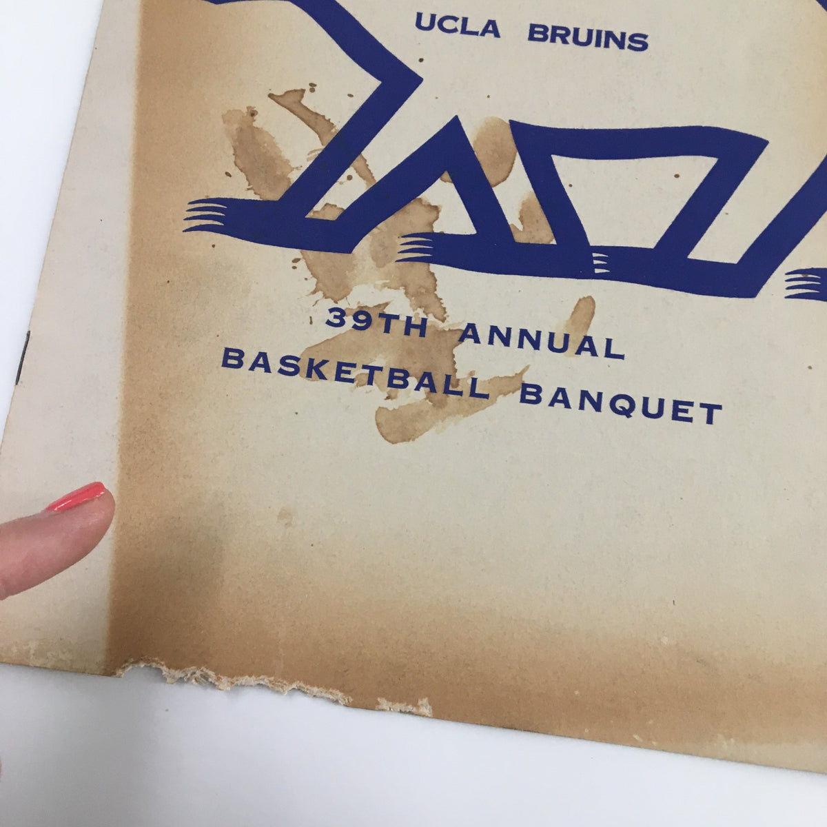 Close-up of the cover of the March 12, 1958 NCAA Basketball UCLA Bruins 39th Annual Basketball Banquet magazine highlighting the UCLA Bruins branding and some signs of wear.