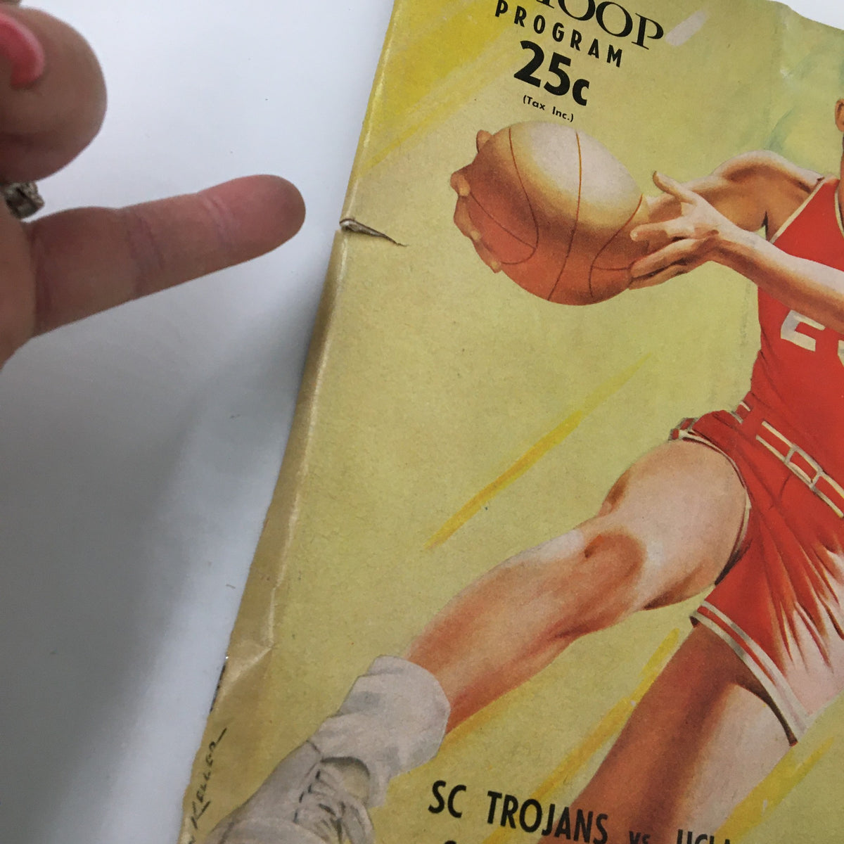 February 17 1962 NCAA Basketball SC vs UCLA Bruins The Hoop Official Program showing detailed edge wear and a hand pointing to the cover.