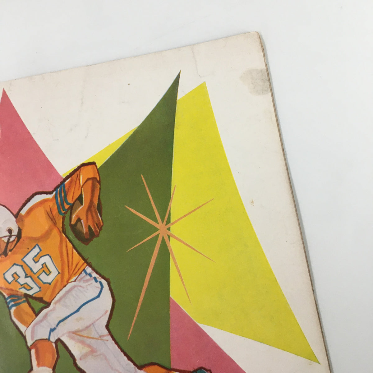 Detail of the cover of the October 23 1959 NCAA Football UCLA Bruins vs Air Force Falcons booklet showing the vibrant starburst design behind the player.