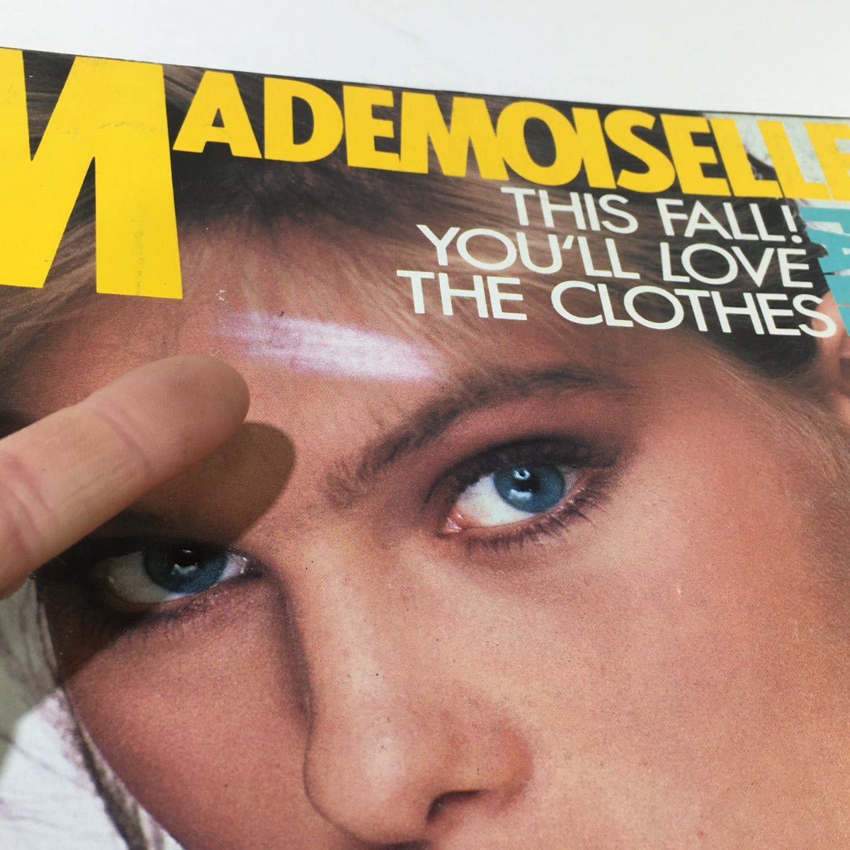 Cover of VTG Mademoiselle Magazine: September 1983 featuring a model with striking blue eyes and the bold title. The cover highlights fall fashion styles with the text 'This Fall! You'll Love The Clothes.' The image showcases the unique vintage appeal of the magazine.