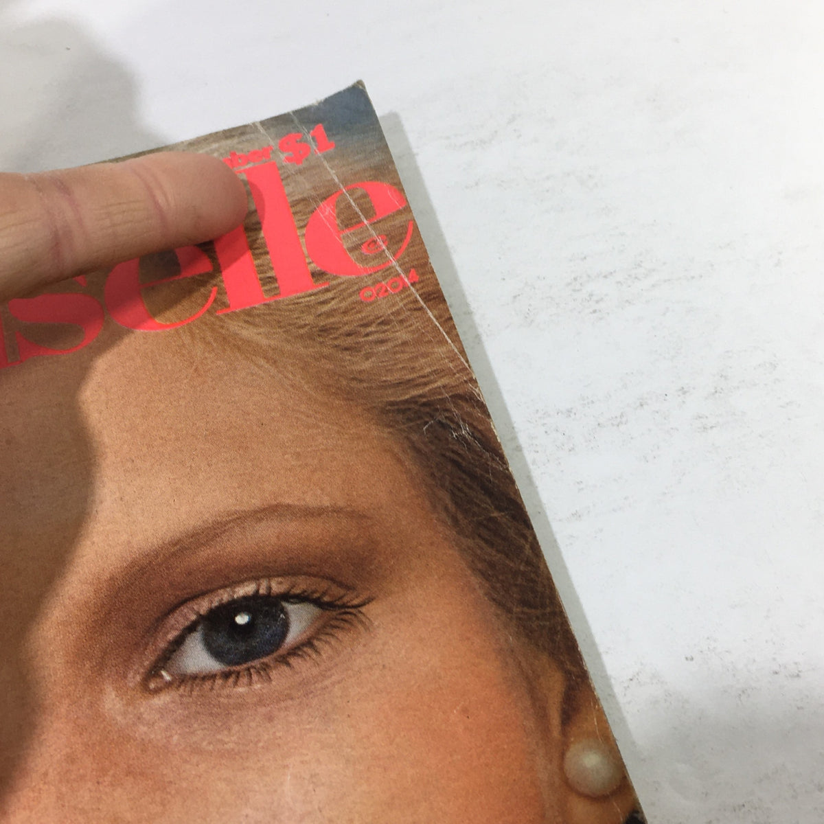Close-up view of the cover of the December 1975 Vintage Mademoiselle Magazine, displaying details of the model's eye and makeup alongside the magazine title, emphasizing beauty tips and lifestyle themes.