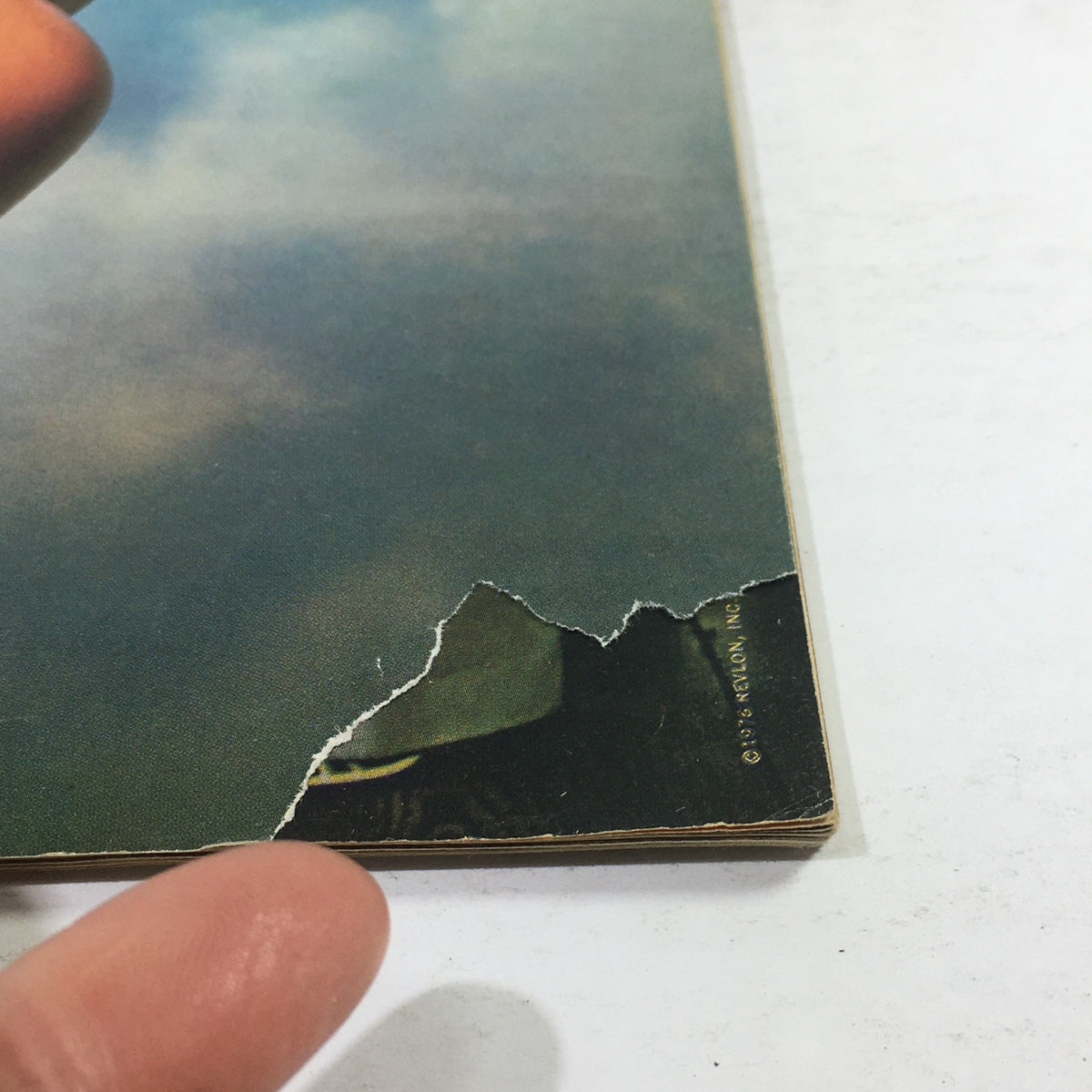 Close-up of the back cover of Essence Magazine June 1976 showing wear and tear, including a torn edge. This vintage magazine is a collector's item showcasing the era's fashion history.