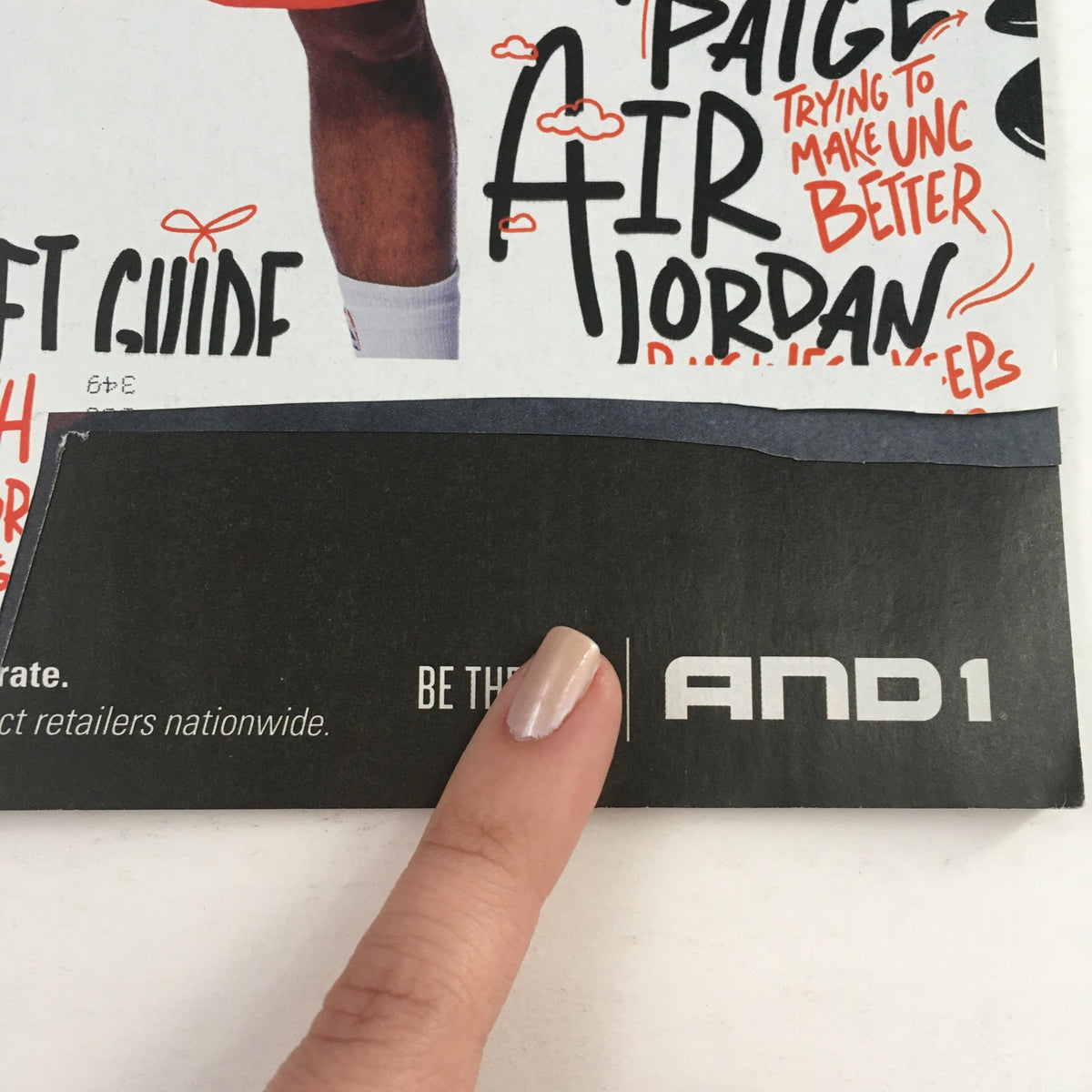 Bottom of the cover page of Slam Magazine February 2015 showing the AND1 logo with a finger pointing at the advertisement.