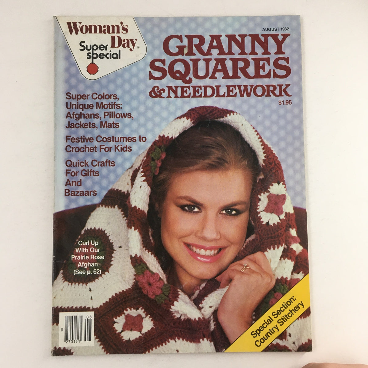 Cover of Woman's Day Magazine August 1982 featuring Granny Squares & Needlework, showcasing a smiling woman wrapped in a colorful crochet blanket, highlighted by the title and various craft project suggestions.