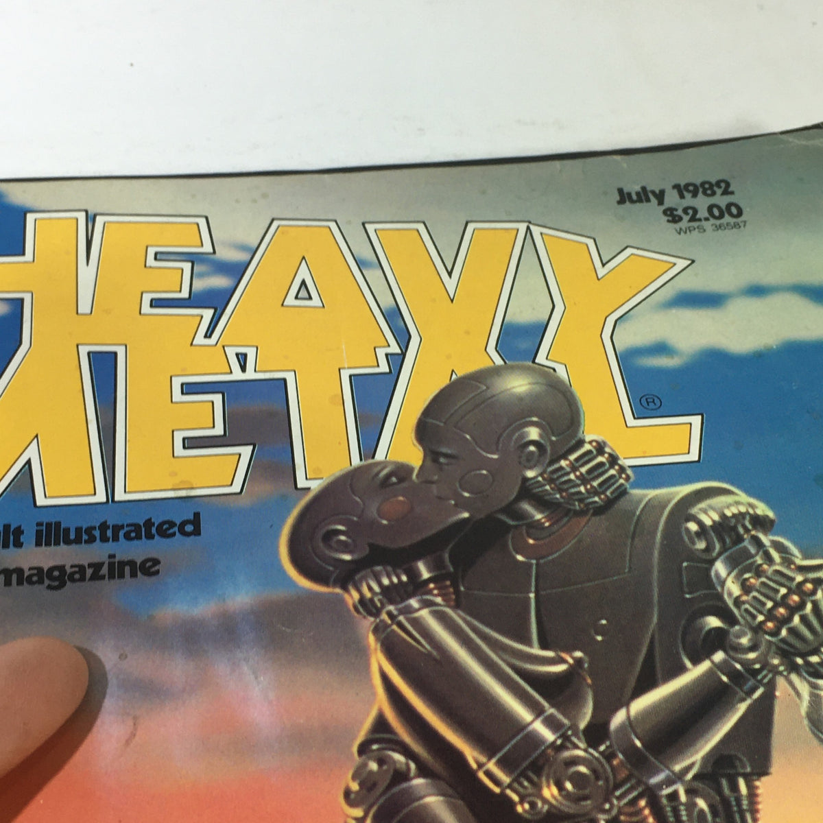 Close-up of the cover of VTG Heavy Metal Magazine: July 1982 - The Adult Fantasy, highlighting the title and the illustrated robot couple in a passionate pose.