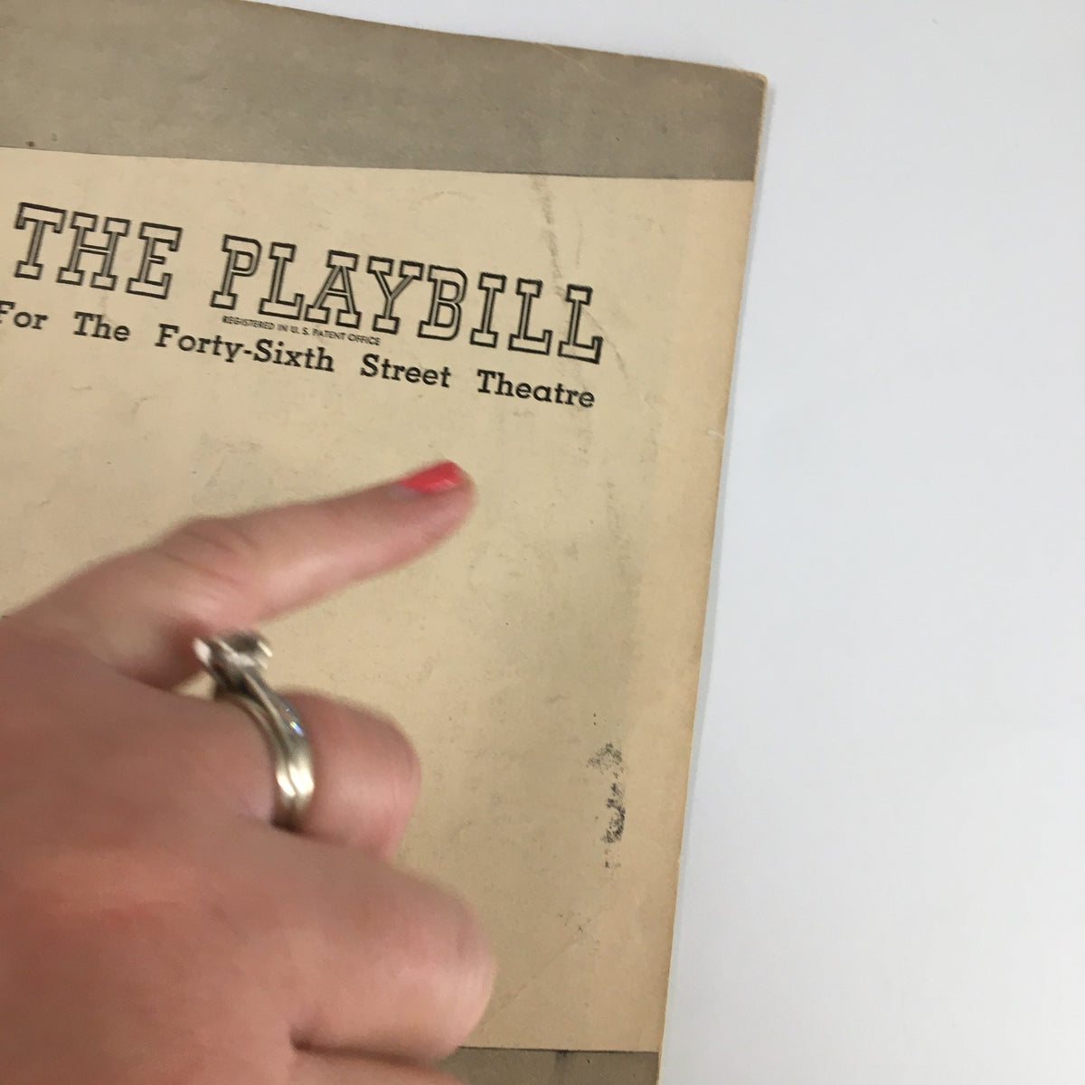 Detail view of the 1948 Playbill for Finian's Rainbow, emphasizing the title and theatre name with a hand pointing at it.
