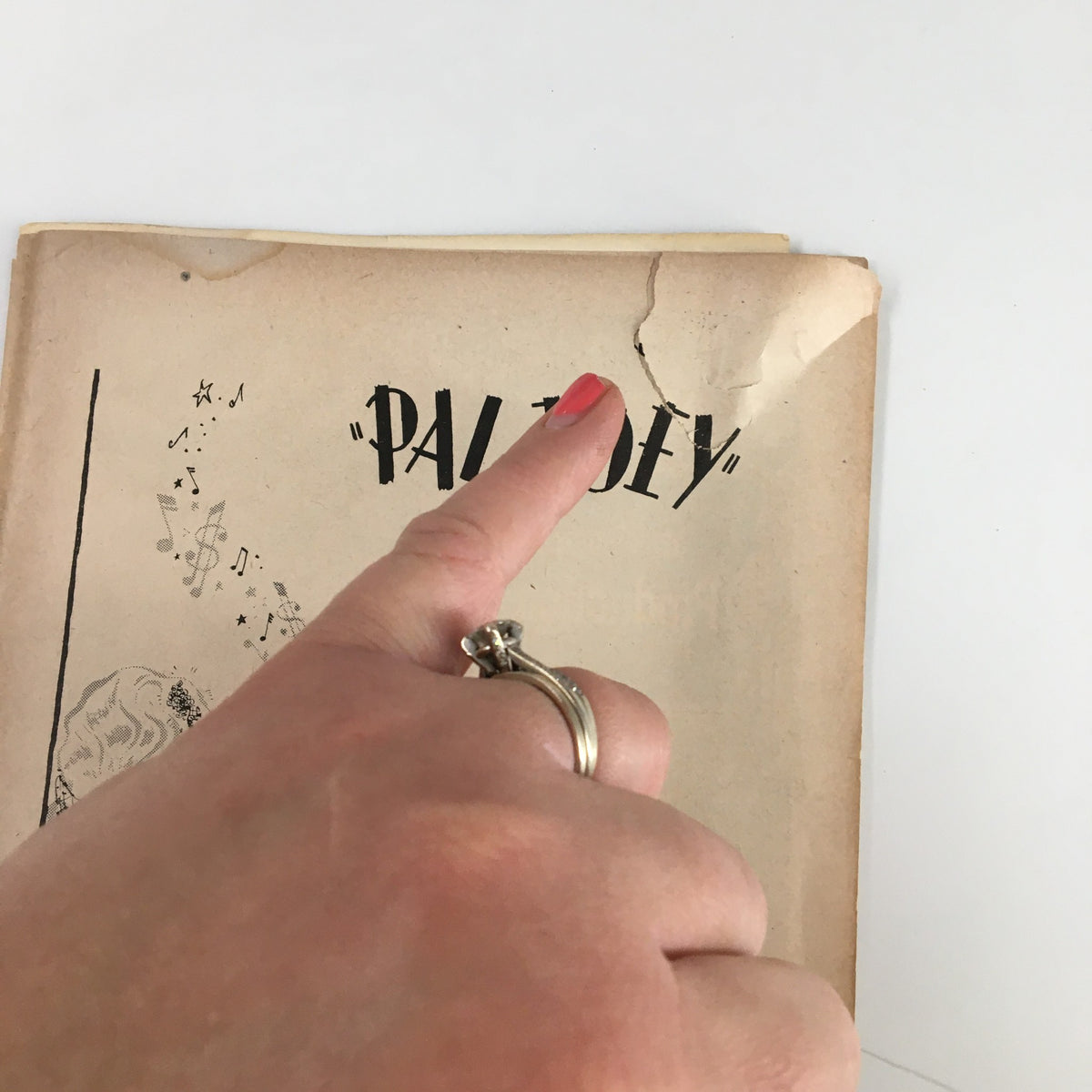 Close-up view of the 1952 Playbill for 'Pal Joey' showing the title and a hand pointing to a crease.
