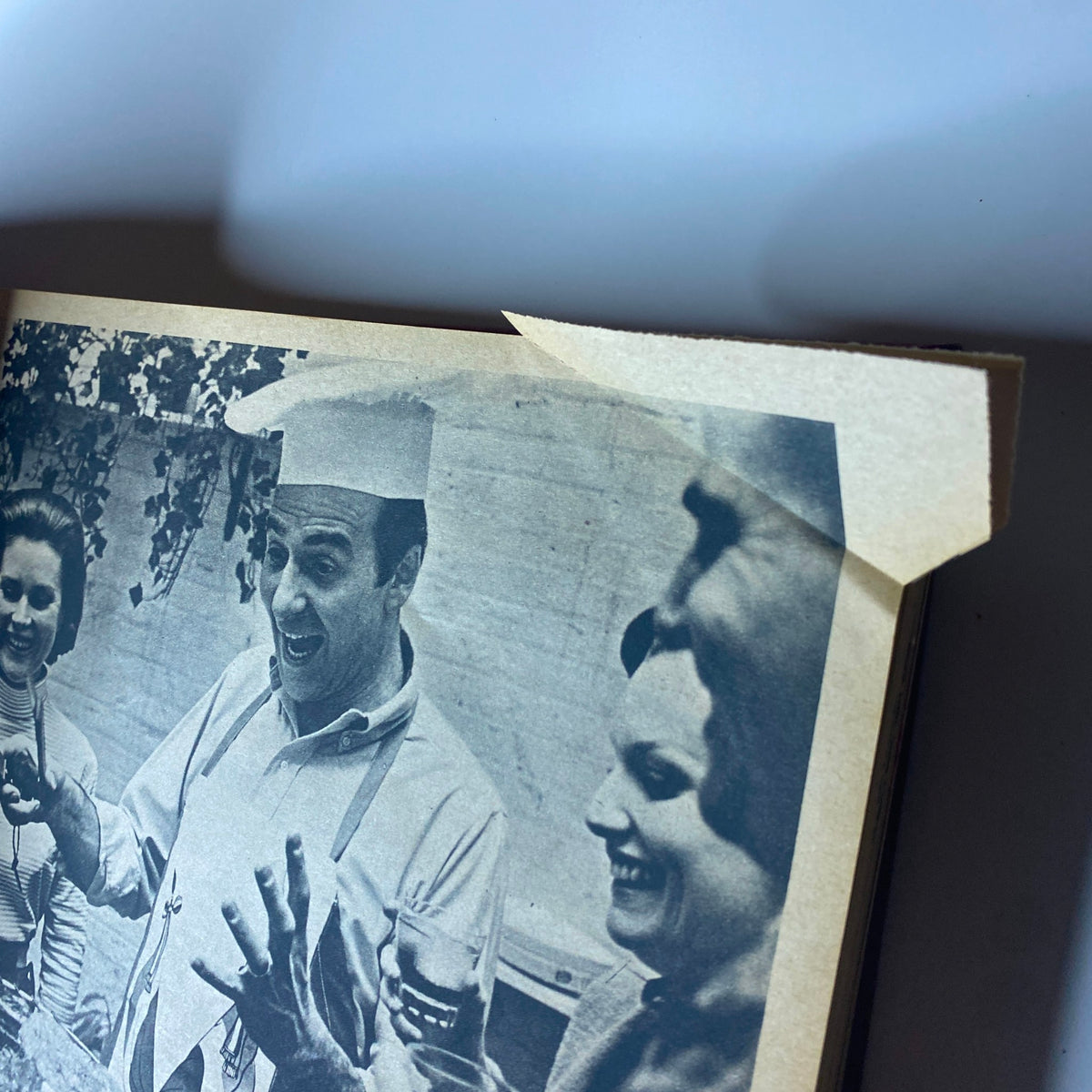 A candid shot from The New York Times Magazine July 1965, capturing a chef in a white hat joyfully engaging with two women at a social gathering.