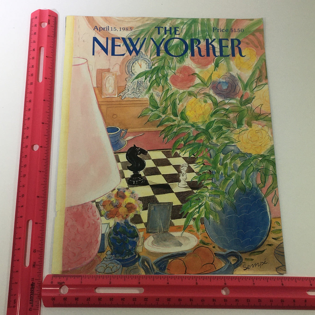Cover of The New Yorker Magazine, April 15, 1985, by Jean-Jacques Sempe, with a ruler for size reference. The illustration includes a chessboard, a colorful flower arrangement, and charming home decor elements.