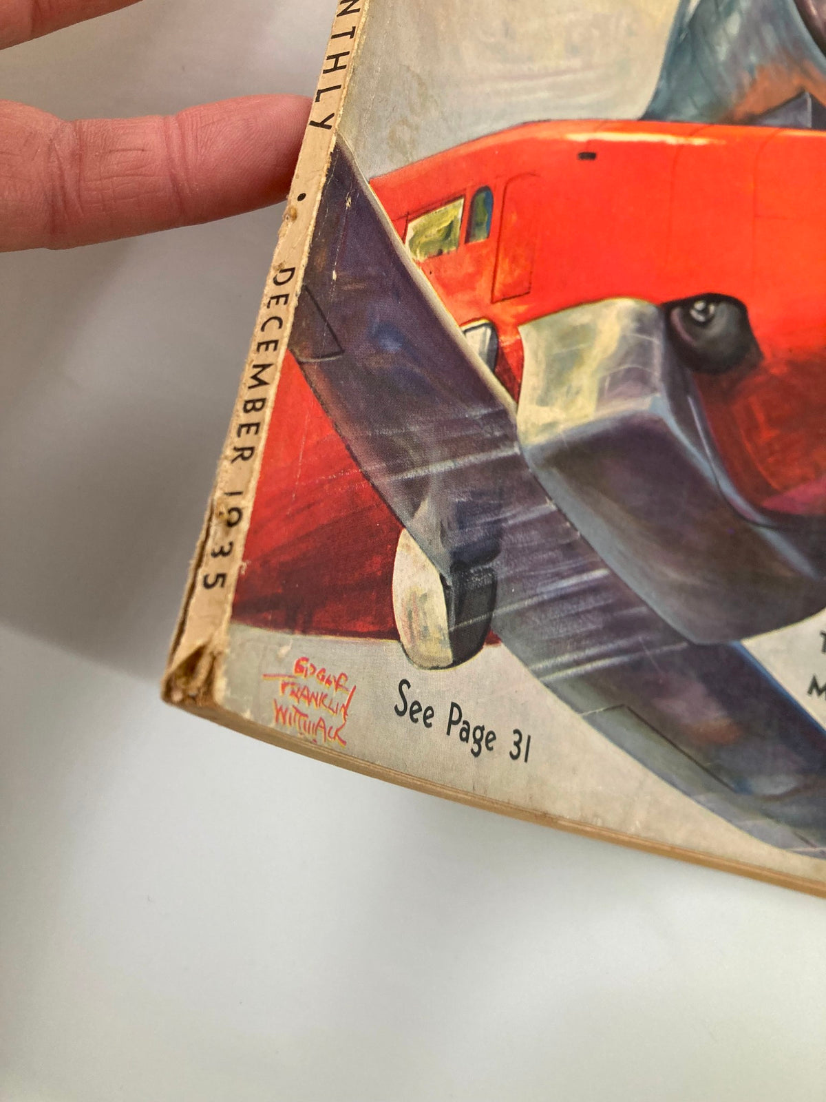 Close-up view of the spine and corner of the VTG Popular Science Magazine December 1935 showcasing the month and year along with the artist's signature.