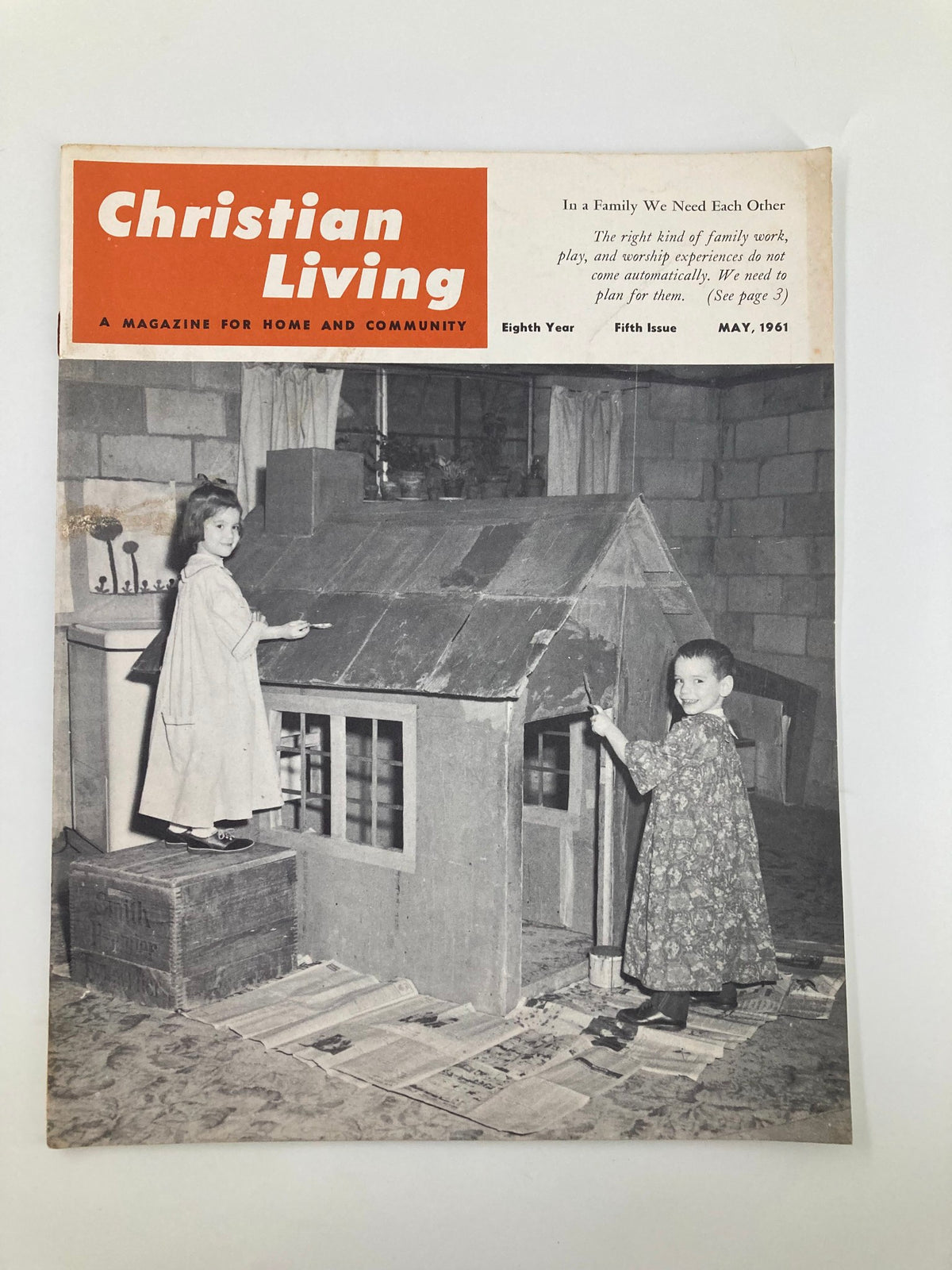 Cover of VTG Christian Living Magazine from May 1961, featuring the theme 'In A Family We Need Each Other'. The image shows two children engaged with a playhouse, highlighting the magazine's focus on family and community dynamics.