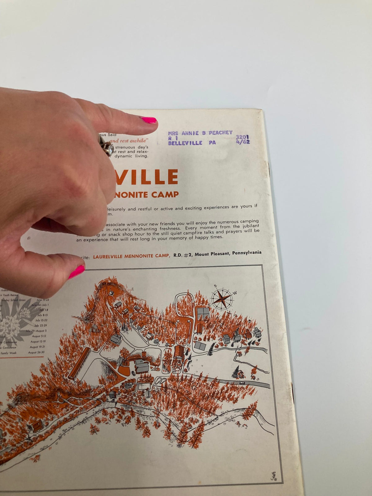 Back cover of VTG Christian Living Magazine May 1961 showing information about Laurelville Mennonite Camp, with a hand pointing to the details.