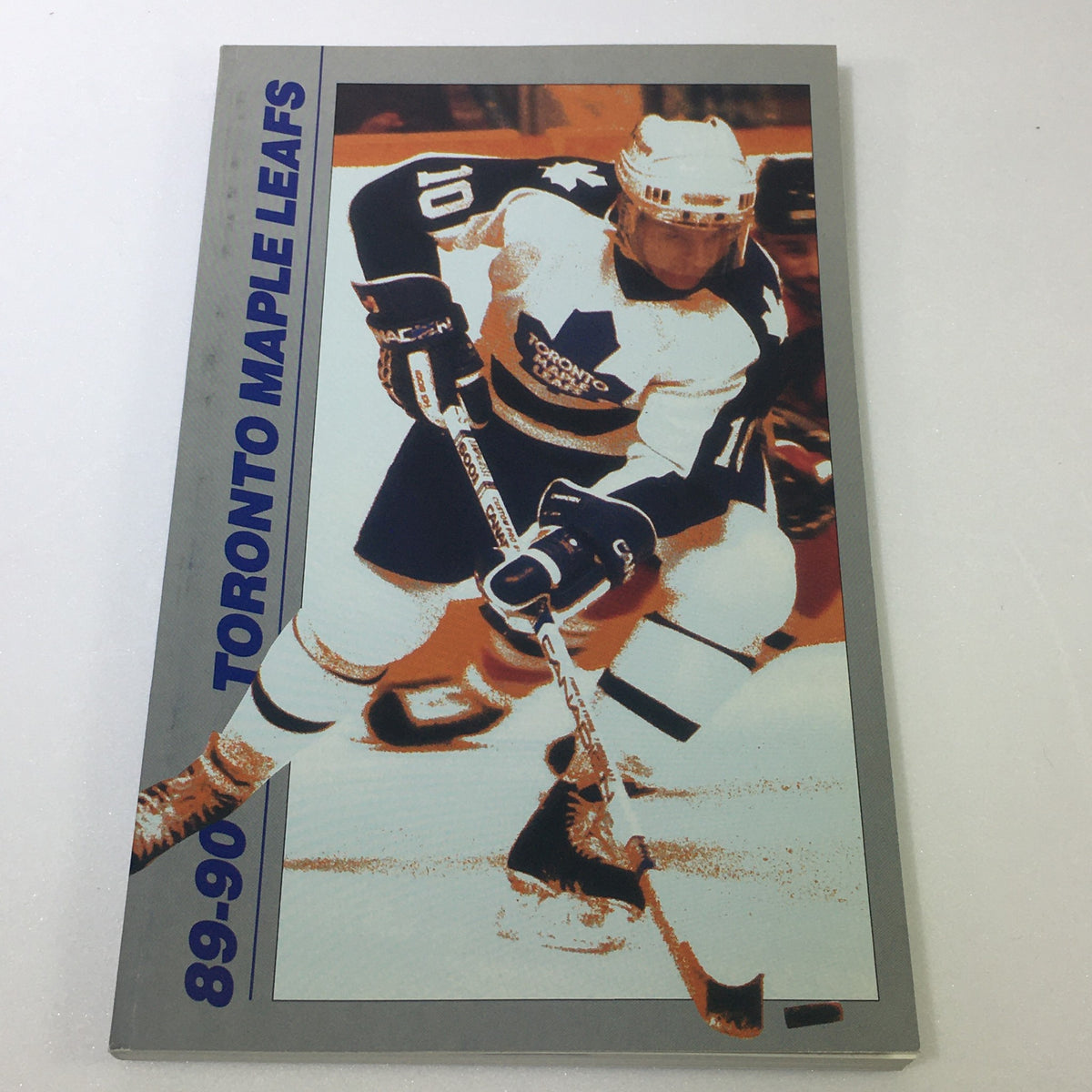 Cover of the 1989-1990 Toronto Maple Leafs Official Fact Book showcasing a player with a hockey stick, an essential item for fans of the Toronto Maple Leafs.