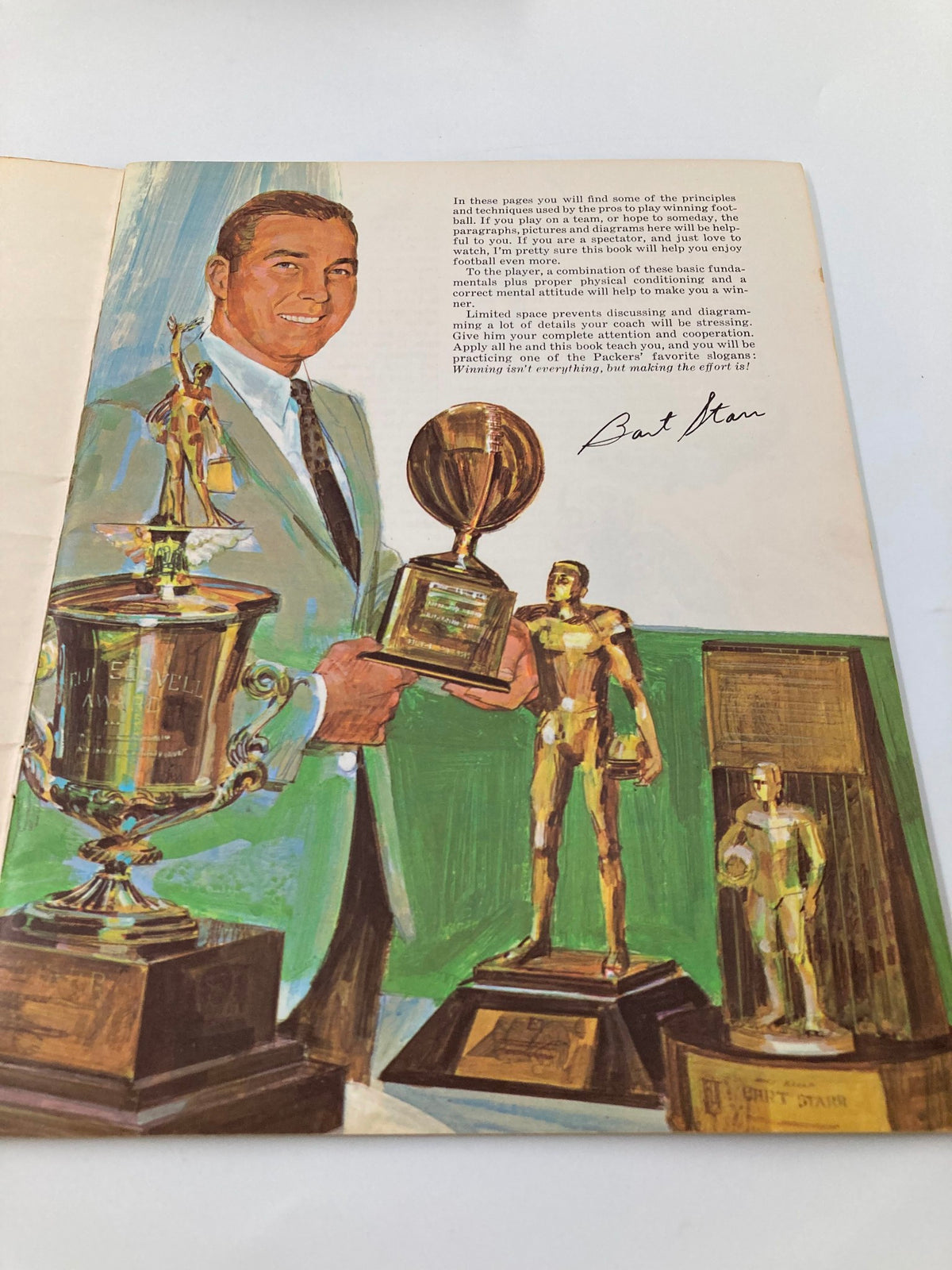 Illustration of Bart Starr holding multiple sports trophies, featured in VTG 1968 Winning Football by Bart Starr, showcasing his achievements.