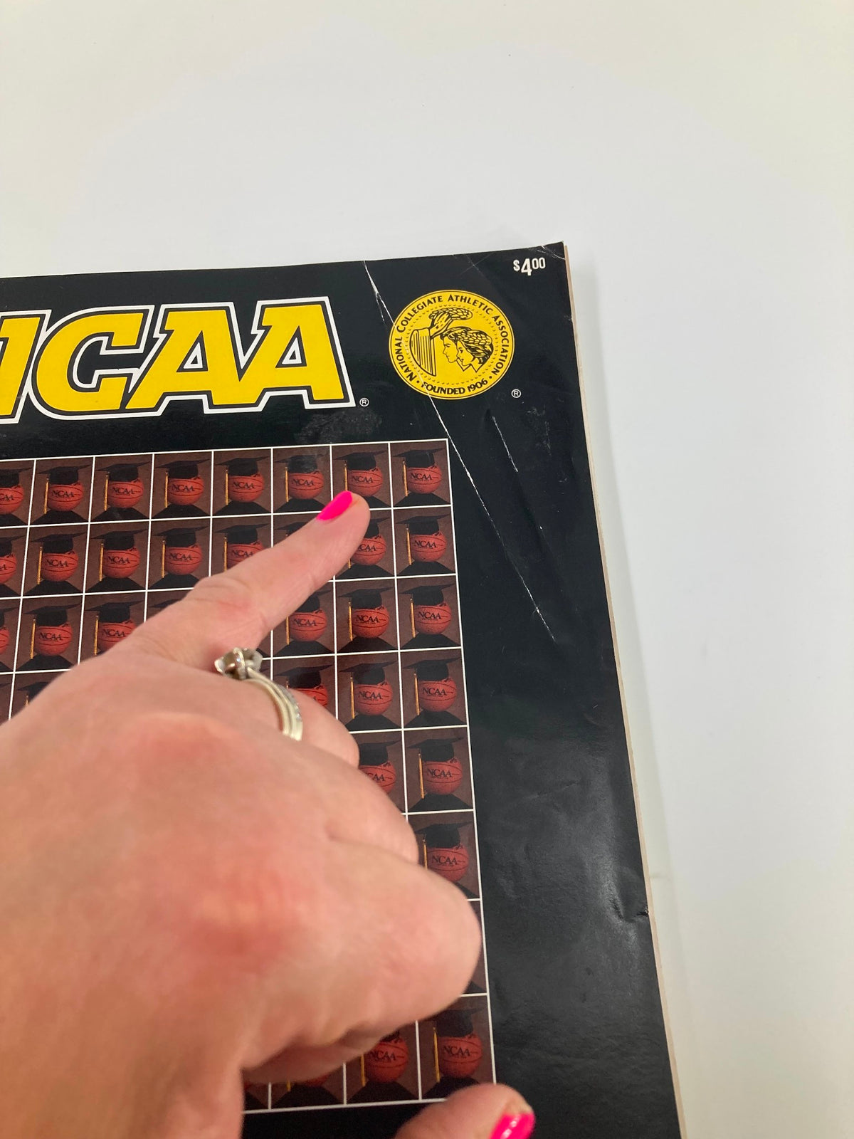 Close-up of the 1990 NCAA Division I Men's Basketball Championship First & Second Rounds program cover showing a hand pointing at the NCAA logo.