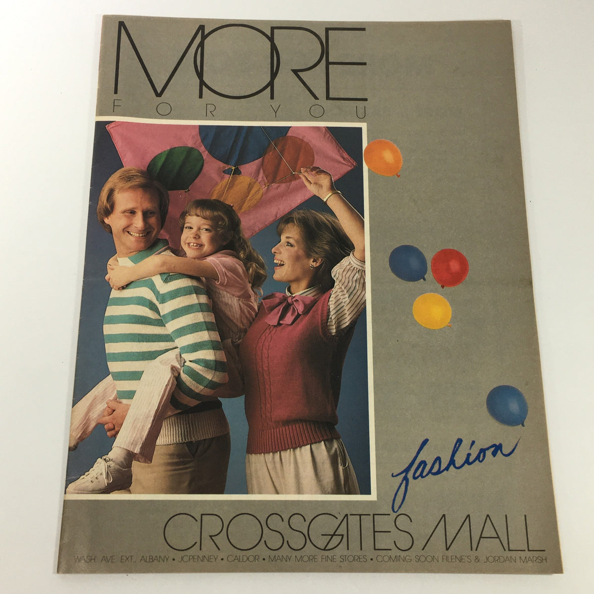 Cover of the VTG 1984 Fashion Crossgates Mall catalog featuring a family portrait with colorful balloons and fashion, representing the style of the era.